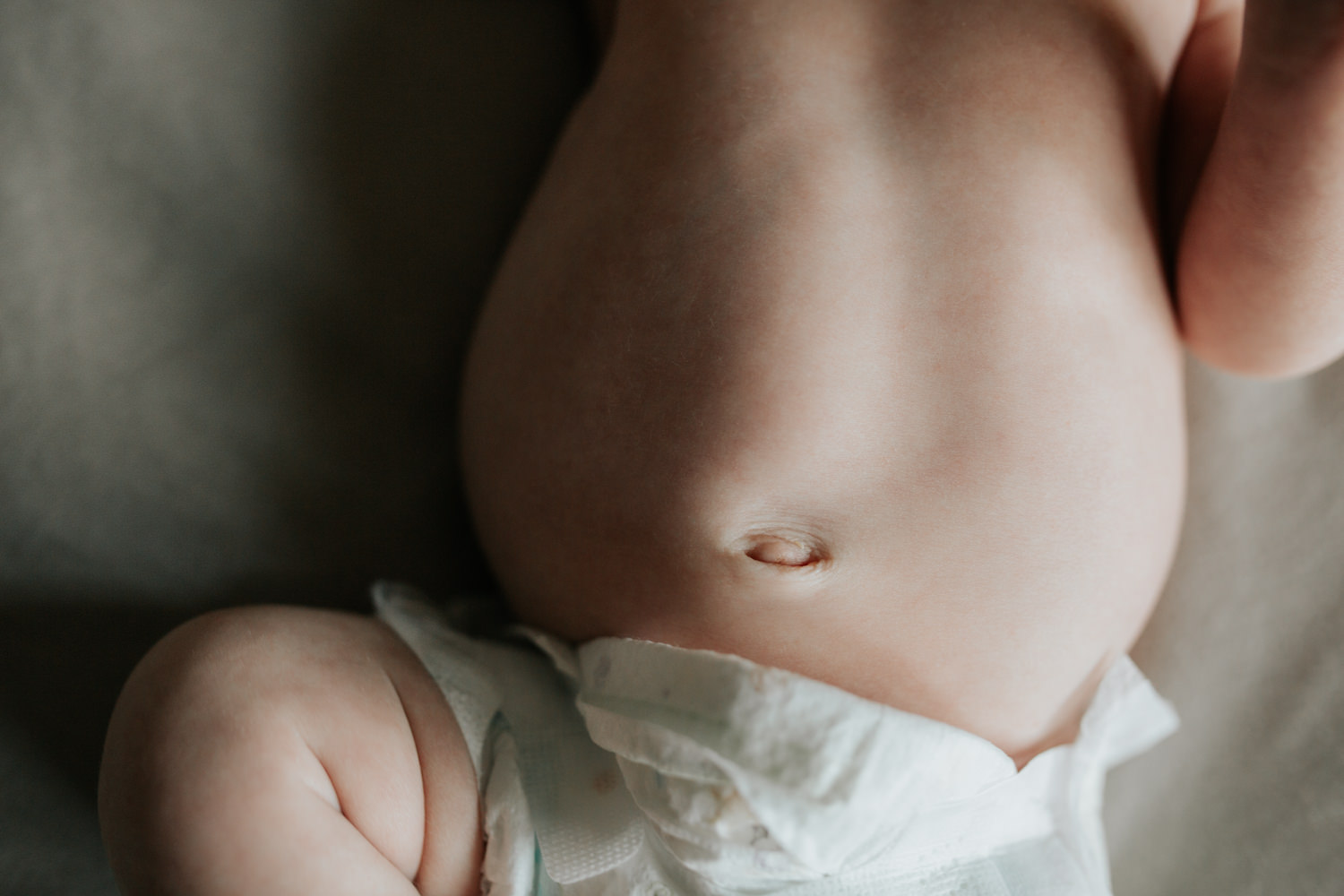 2 week old baby girl in diaper lying on bed, close up of bellybutton - Barrie In-Home Photos