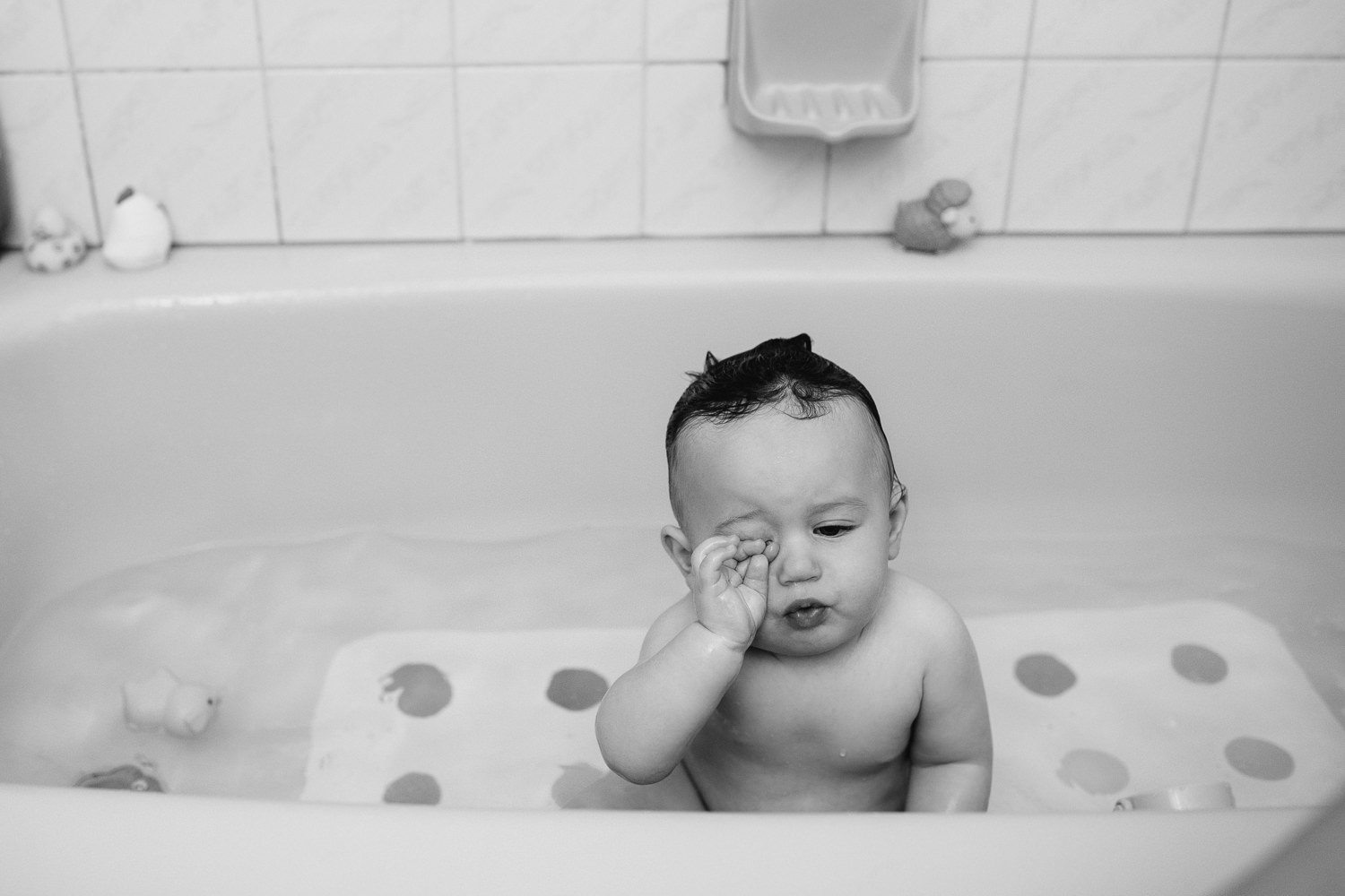 9 month old baby boy with dark hair sitting in bathtub rubbing eyes - GTA Golden Hour Photos