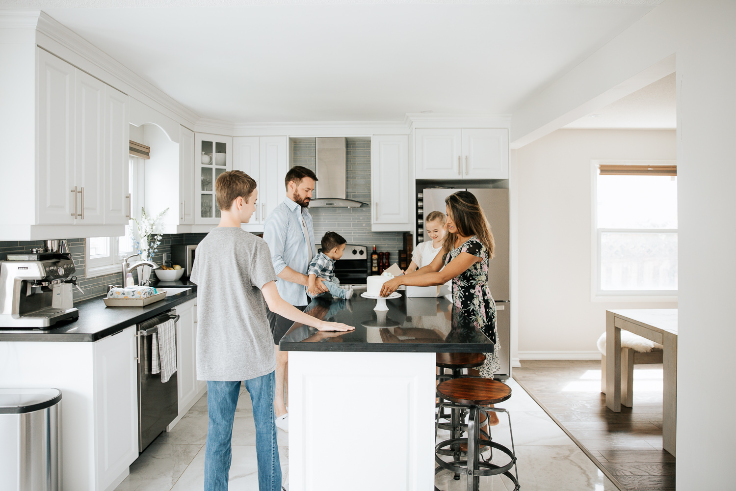 family of 5 in neutral kitchen preparing cake for 1 year old baby boy's cake smash - York Region Lifestyle Photography