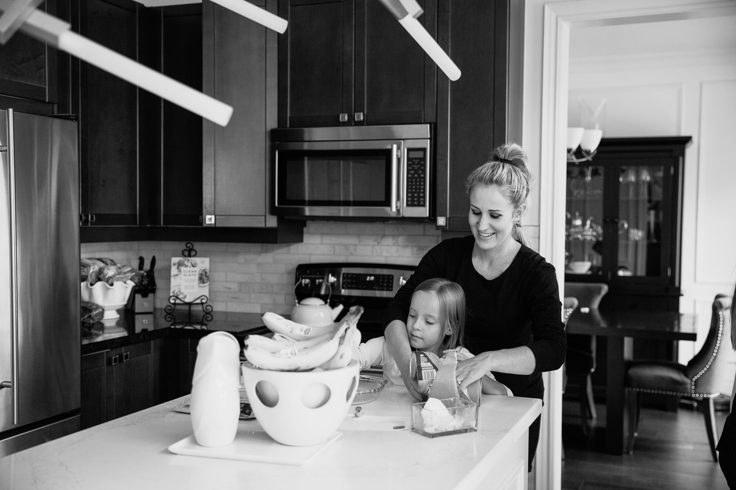 mom and 8 year old girl standing at kitchen island together, mother with arms around daughter preparing food - Barrie In-Home Photos