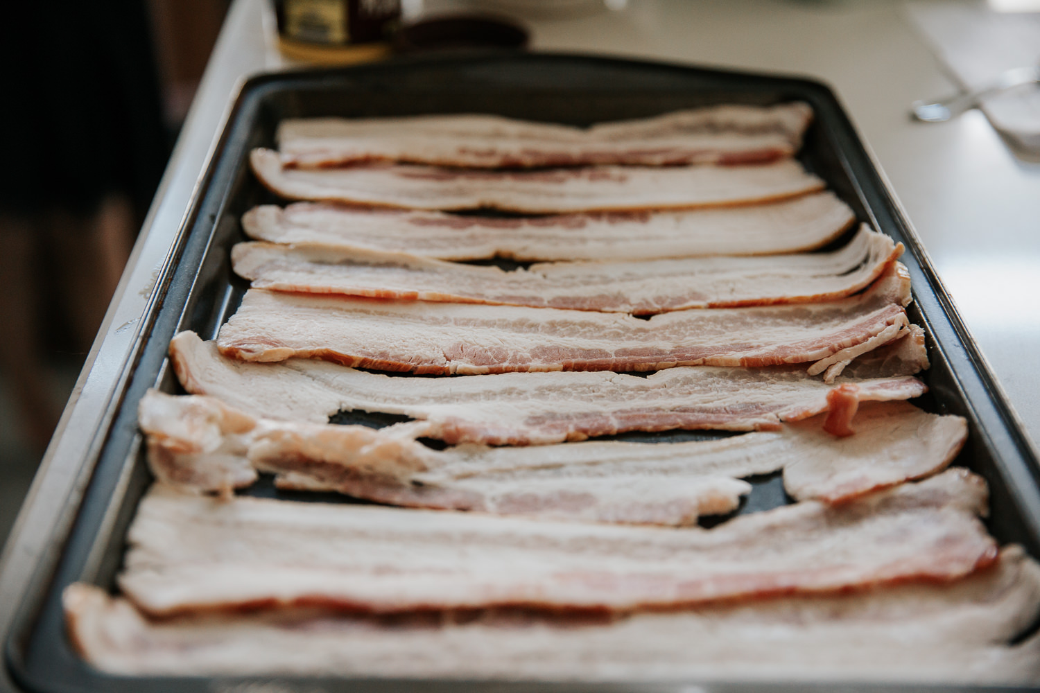 raw bacon for brunch laid out in rows on pan - Newmarket Lifestyle Photos