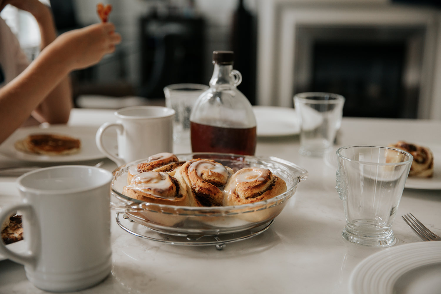 cinnamon buns covered in icing sitting in glass pie dish on table for family brunch - Newmarket Lifestyle Photos