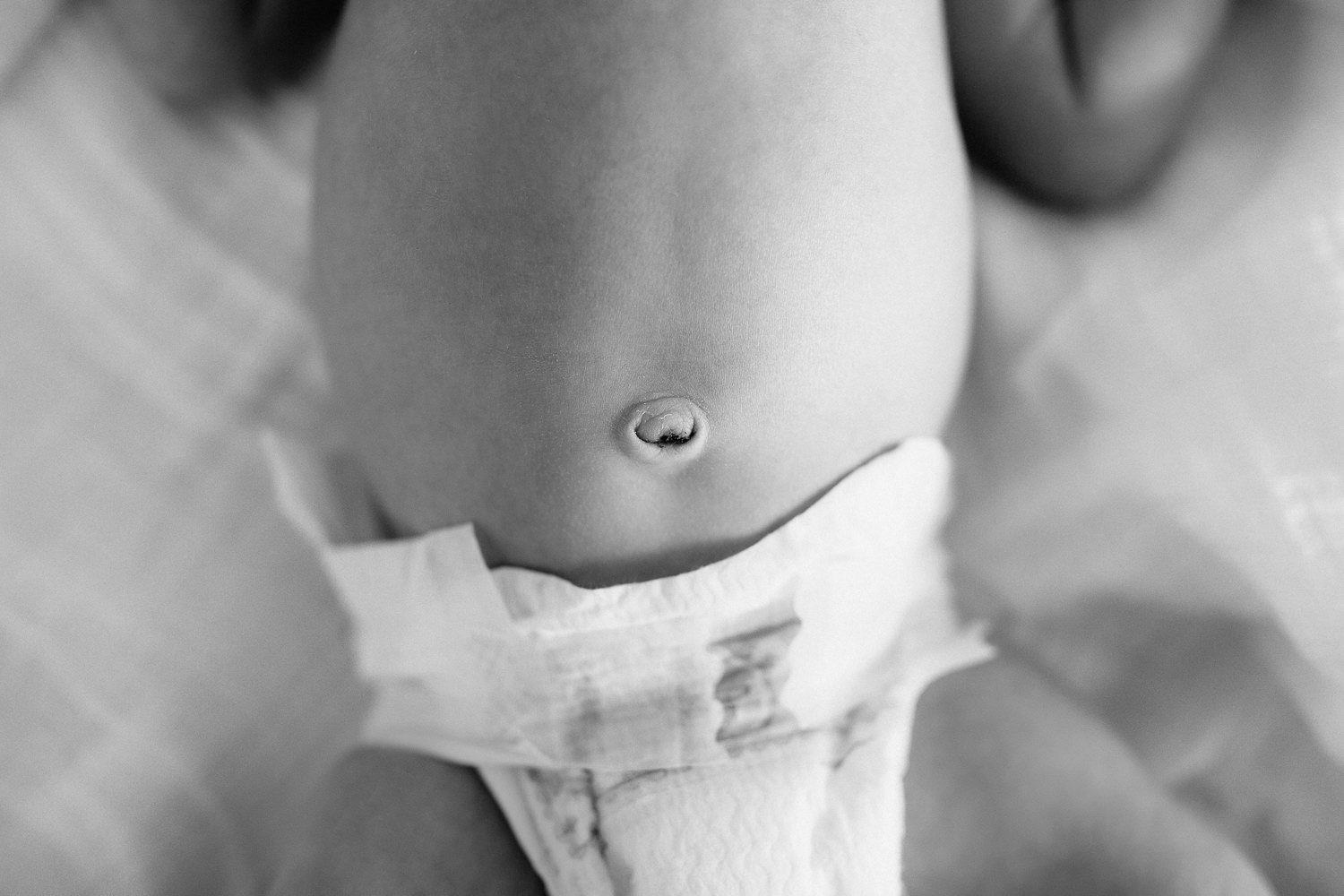 2 week old baby boy lying on bed in diaper, close up of bellybutton - Markham In-Home Photos