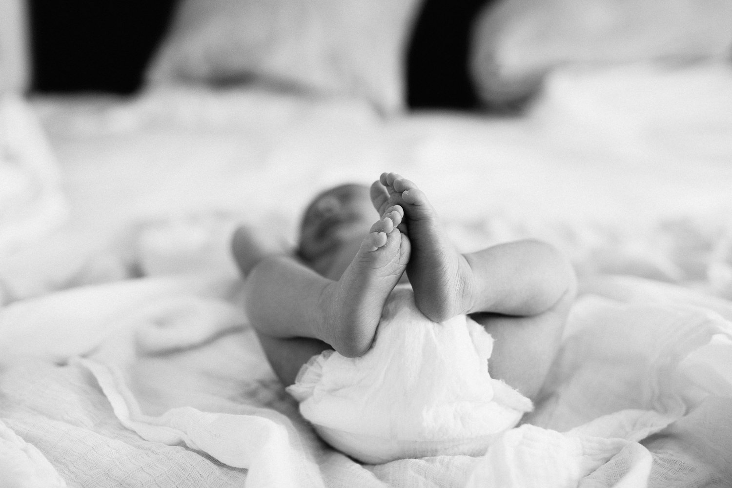 2 week old baby boy lying on bed in diaper, close up of feet - Barrie In-Home Photos