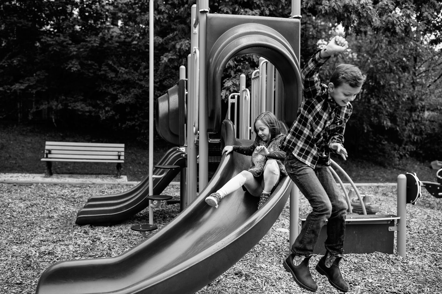 9 year old boy jumping off slide at city park, 7 year old girl sliding down in background - GTA Lifestyle Photos