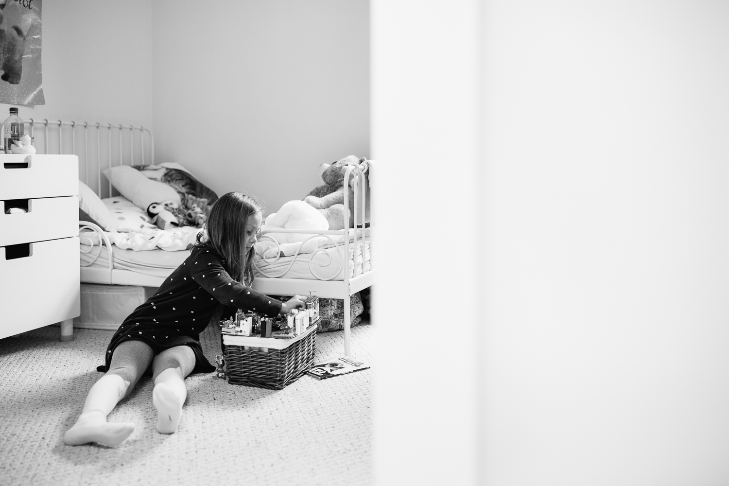 7 year old girl with brown hair wearing polka dot dress sitting on floor of bedroom playing with lego - Barrie In-Home Photos