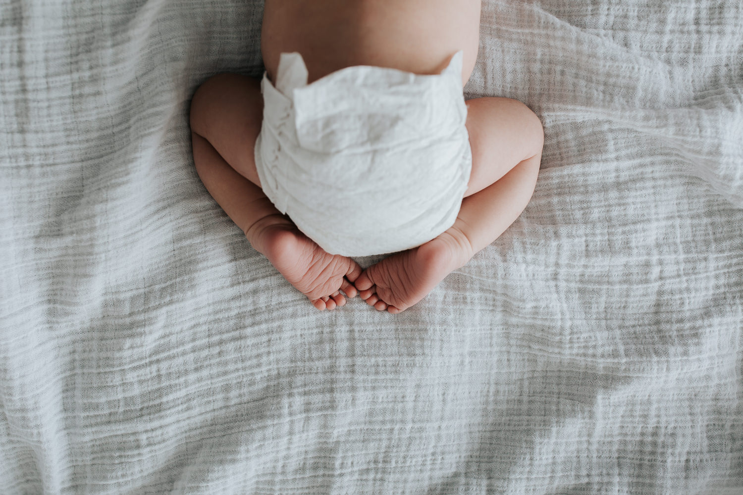 Newmarket In-Home Photography2 week old baby boy in diaper lying on stomach, legs tucked in, close up of feet and toes - 