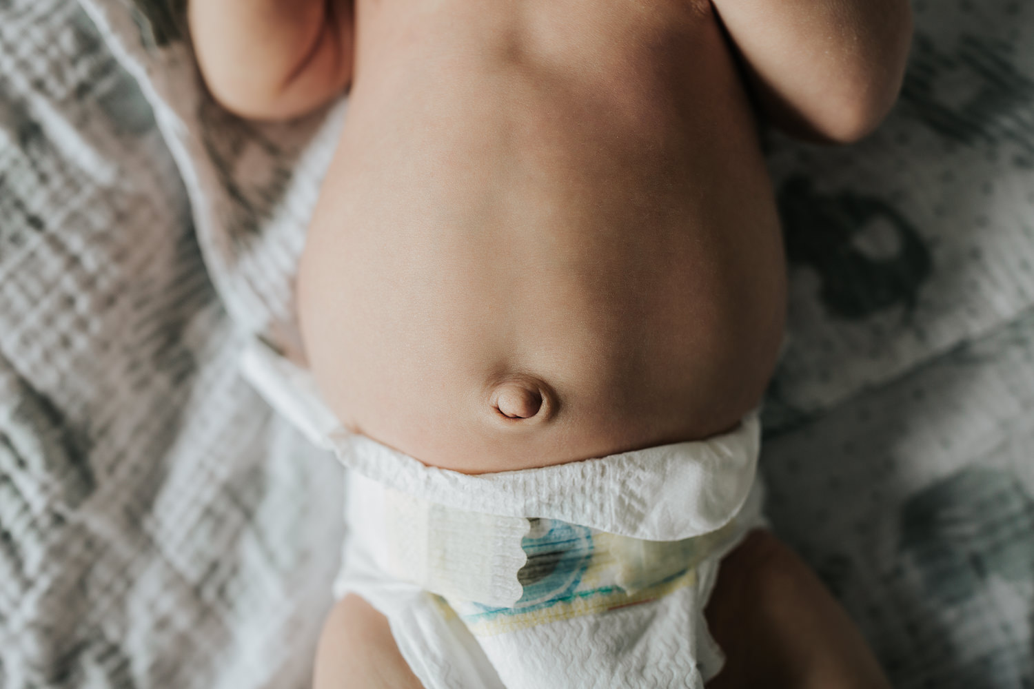 close up of 2 week old baby boy's bellybutton as he lies on bed - Markham In-Home Photos 