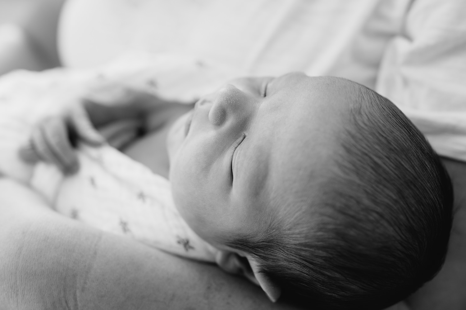 close up of 2 week old sleeping, swaddled baby boy with dark hair lying in his mom's arms - Barrie Lifestyle Photography