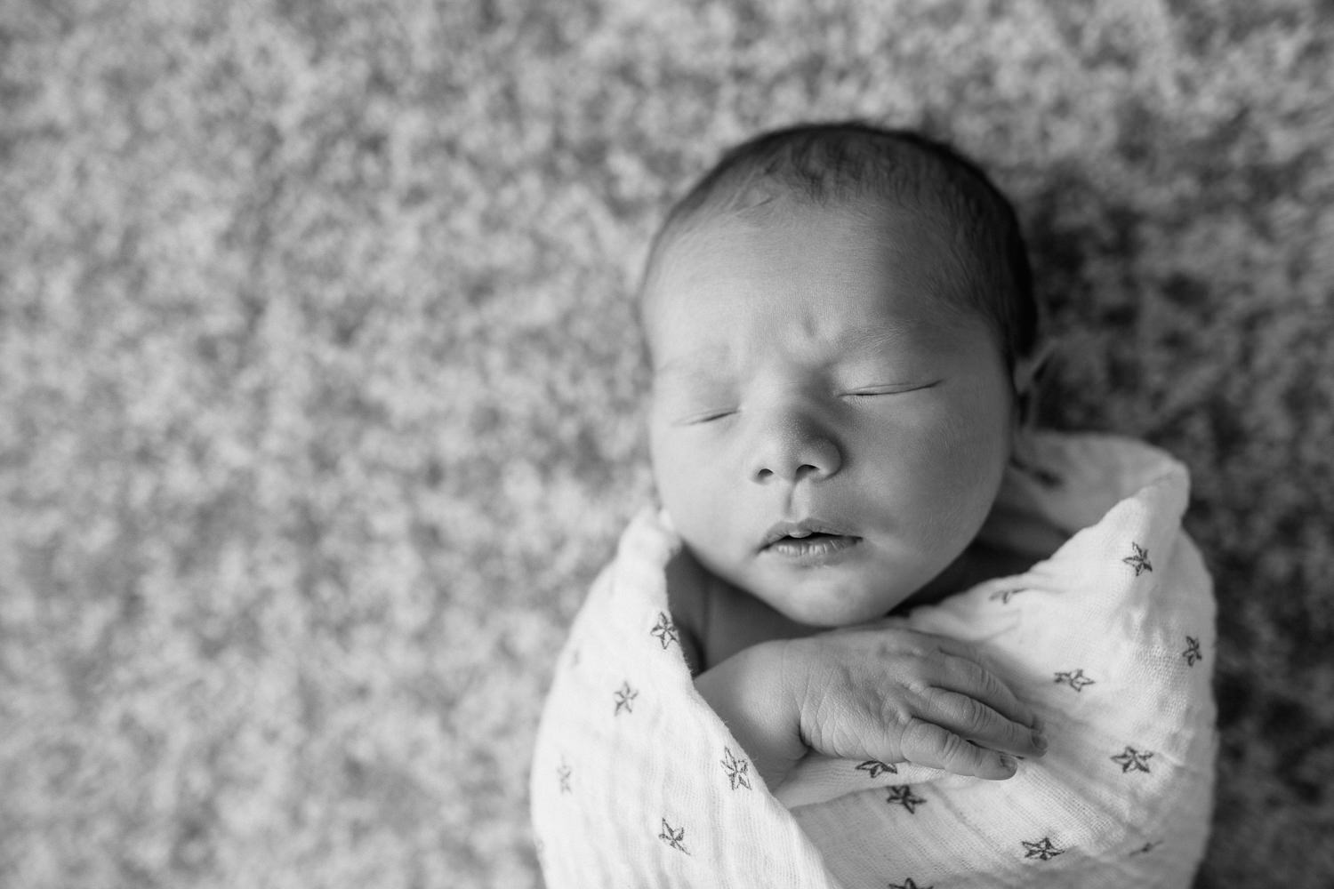 2 week old baby boy with dark hair and olive skin wrapped in swaddle with star on it, sleeping with hand near face - GTA In-Home Photos