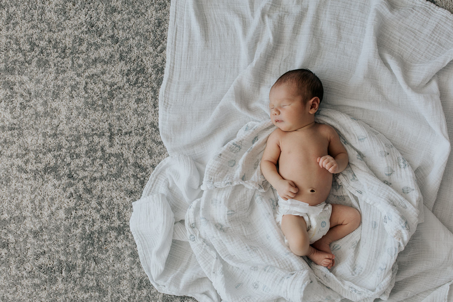 sleeping 2 week old baby boy in diaper lying on swaddle, head to side, hands resting on stomach - Markham Lifestyle Photos