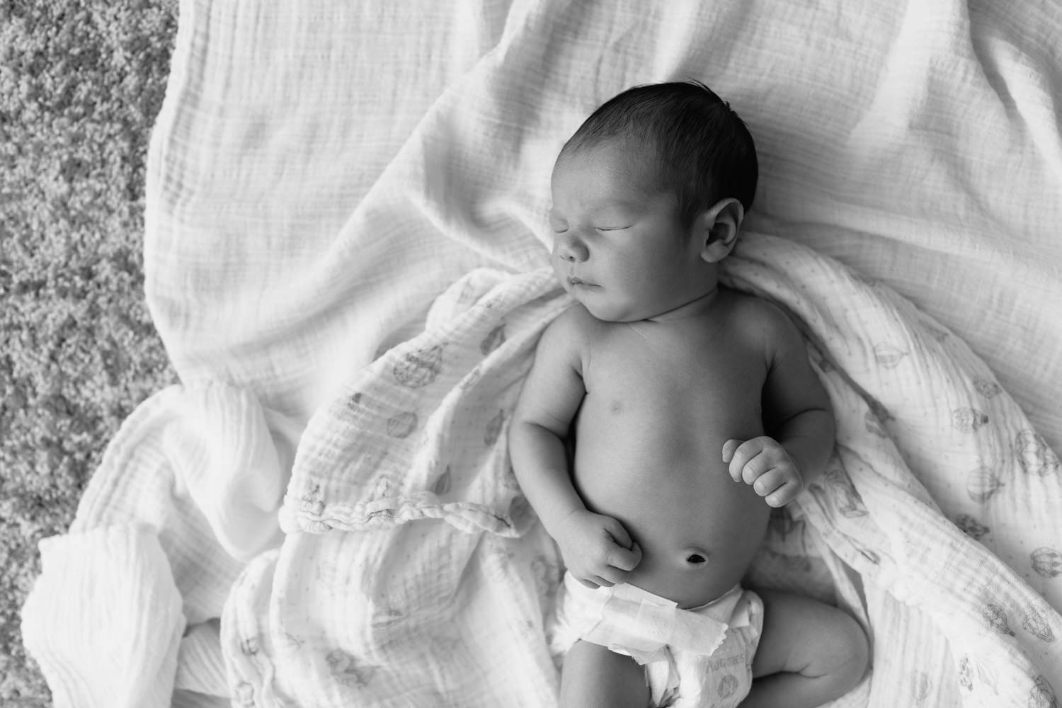 sleeping 2 week old baby boy in diaper lying on swaddle, head to side, hands resting on stomach - Stouffville Lifestyle Photography