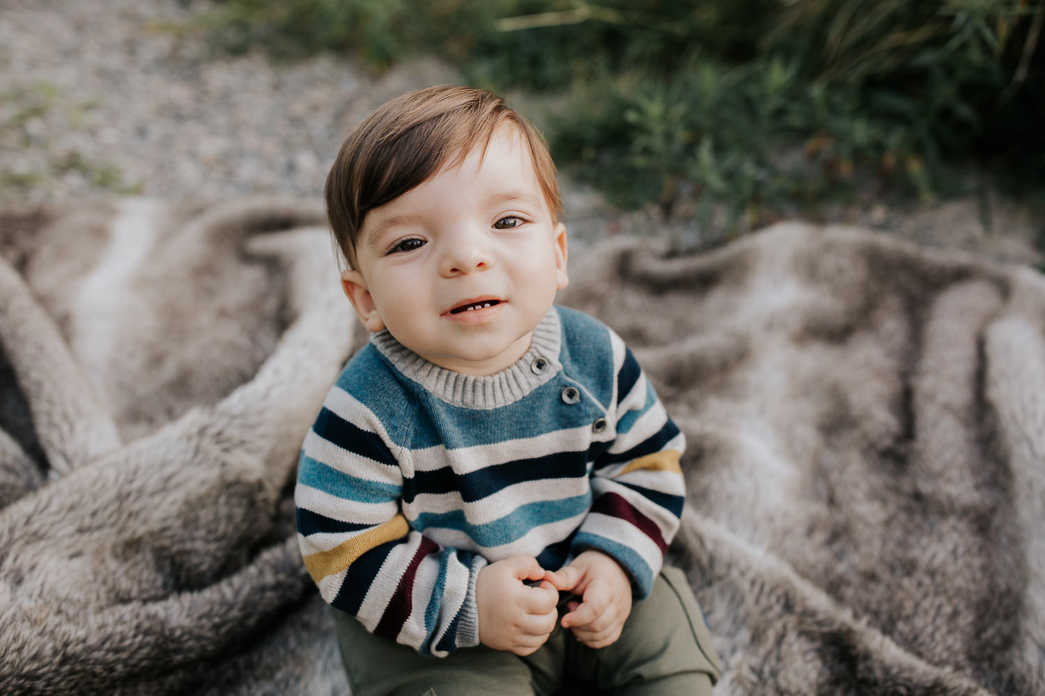 1 year old boy with brown hair and eyes wearing striped sweater sitting on blanket in outdoor path looking up at camera - Newmarket Golden Hour Photos