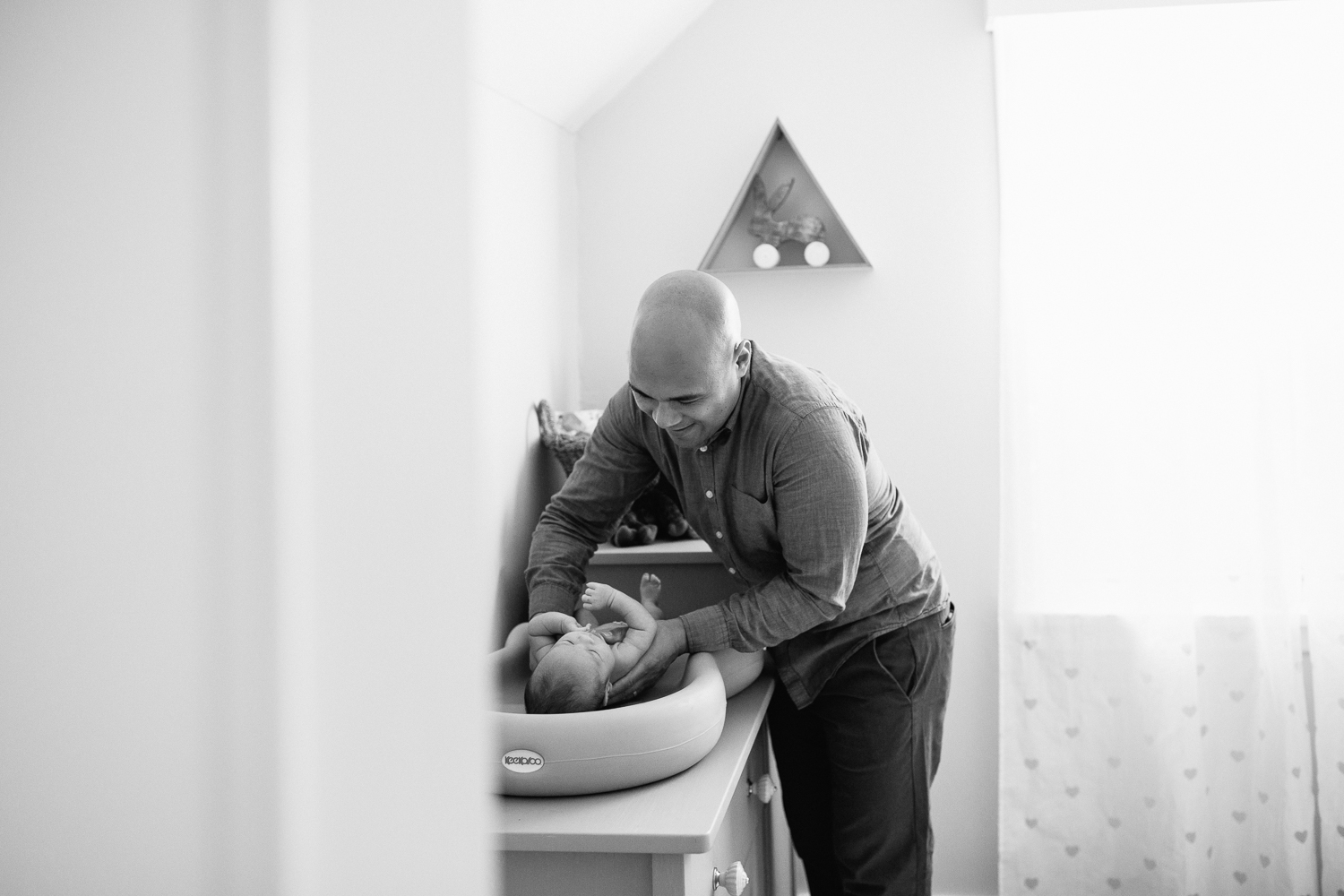 first time dad lying 3 week old baby boy on change table, dad smiling at son - Markham In-Home Photography