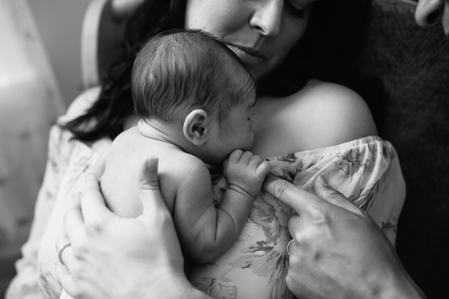 2 week old baby boy in diaper cuddled to mom's chest, holding onto dad's finger - Newmarket In-Home Photography