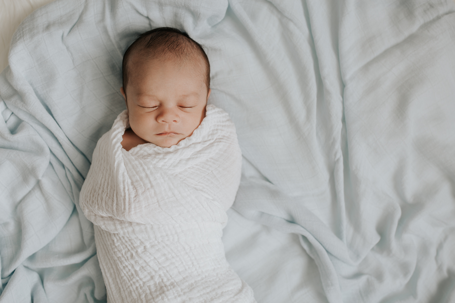 3 week old baby boy with dark hair sleeping wrapped in white swaddle, portrait - Markham In-Home Photography