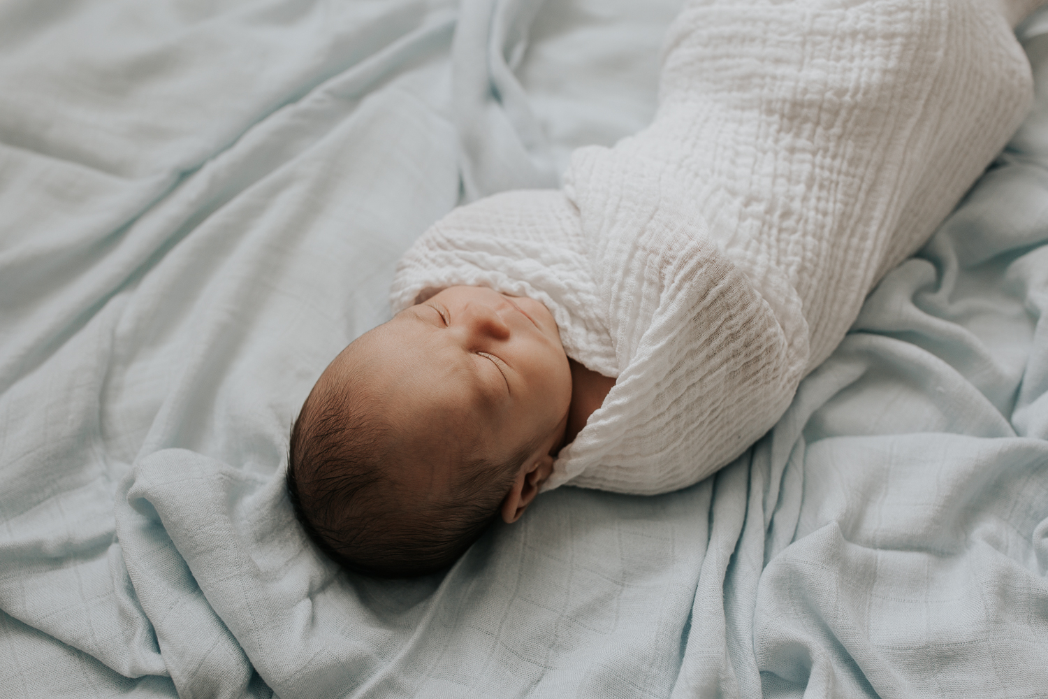 3 week old baby boy with dark hair sleeping wrapped in white swaddle, portrait - GTA In-Home Photography