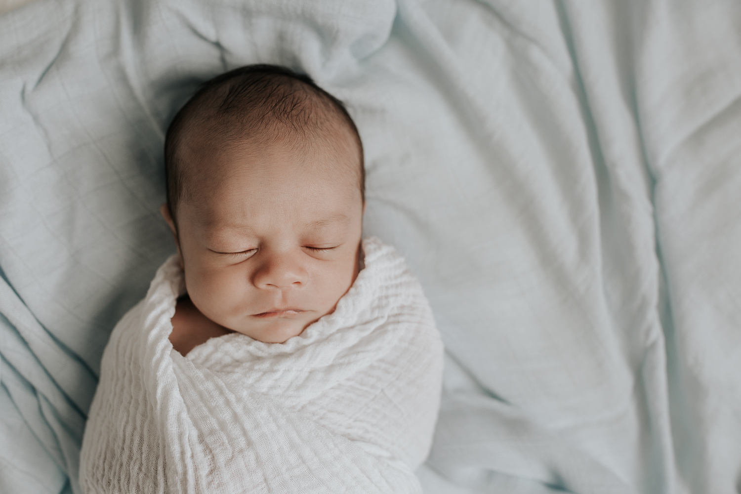 3 week old baby boy with dark hair sleeping wrapped in white swaddle, portrait - York Region In-Home Photography