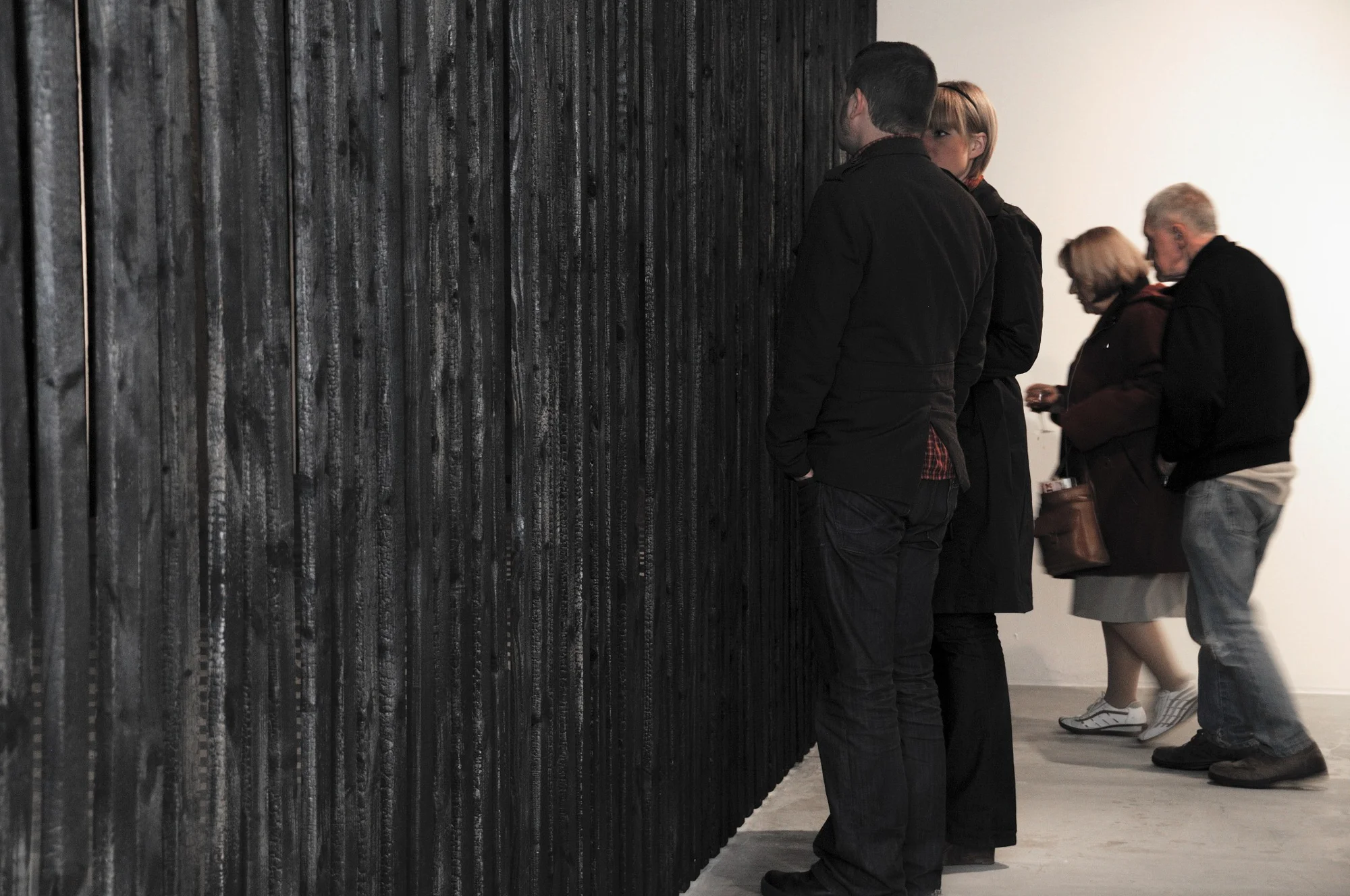 In preparation for Heather and Ivan Morison’s exhibition The Black Line , Void underwent massive physical alterations. Four walls were demolished in the gallery spaces to reveal the underlying skeletal structure. What remained were the raw stripped steel struts, cabling and the original red brick walls of the city factory. A reminder of what the space once was. The Morison’s approach to the exhibition at Void and its space is greatly influenced by the earlier works of artist/writer Robert Irwin, especially his work 'Black Line Volume'. Irwin's aim was to isolate the art experience, to clear his work of any and all concrete manifestations so that it could be reduced to pure phenomenon. In light of this, The Morison’s work at Void aimed to dissolve the spaces into each other, the building and the street. Extensive work was carried out to remove the boundaries that the gallery walls had created revealing the space beyond. The installation however did not end there, the walls were replaced with charred vertical timbers. The outside wall on the street side of the gallery was knocked through where a window once was, an existing window on the other side of the basement was also removed creating two diffused light sources either side of the space, obliquely visible through the slatting. Void gallery