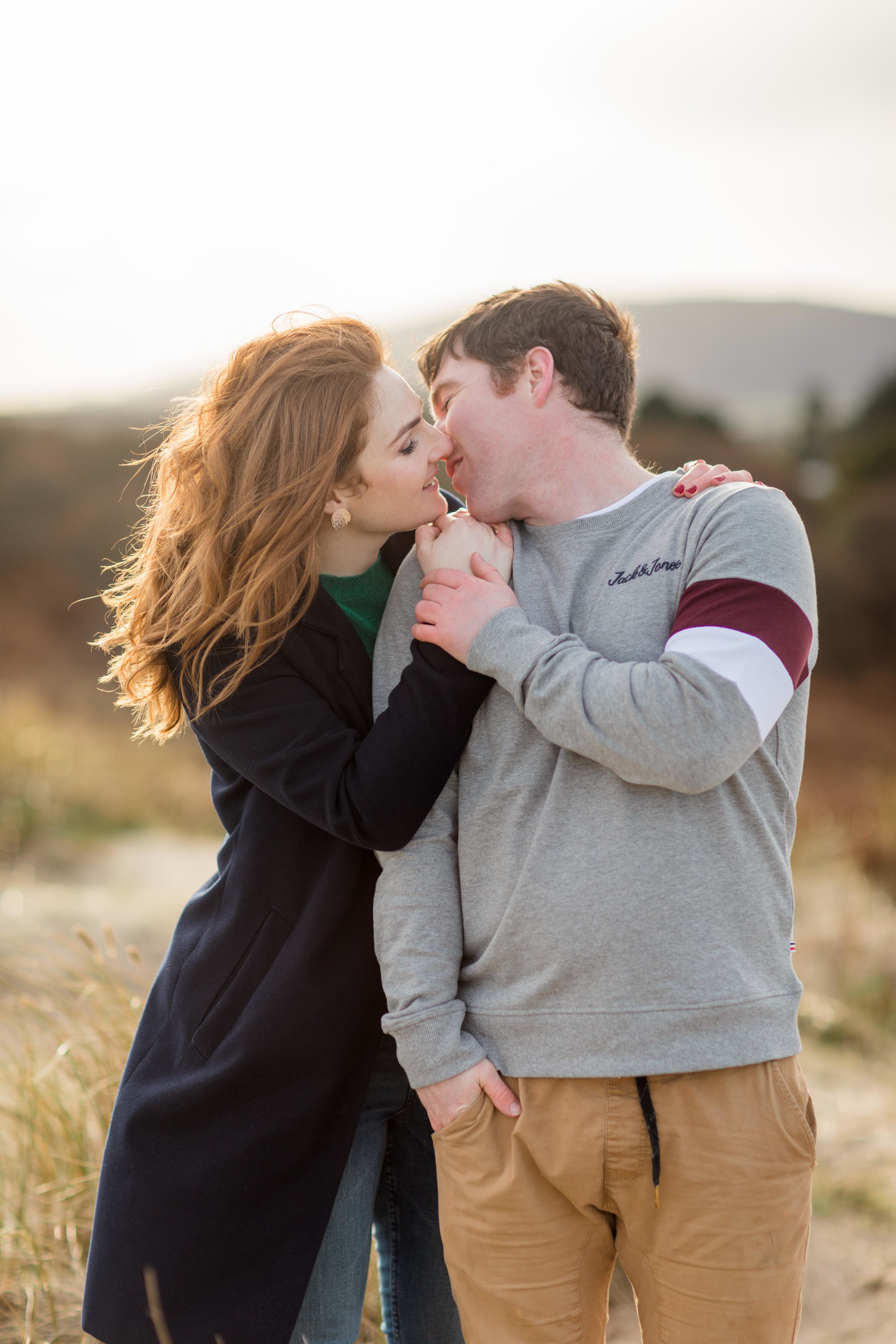 a couple kissing red shoulder length hair posing for an engagement photoshoot in ireland