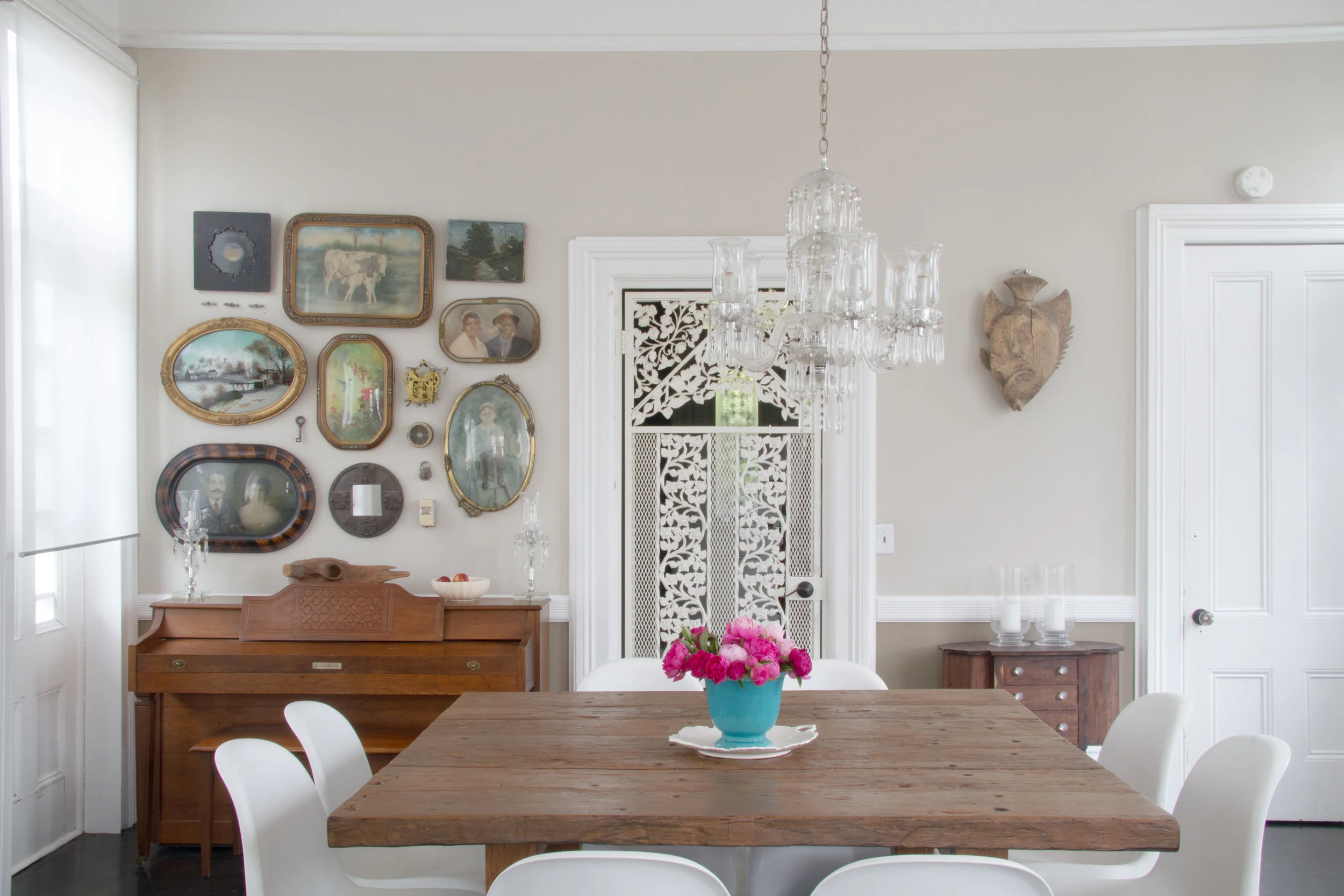 (2/21) The dining room facing the front of the house with its original, likely 1940s, chandelier is juxtaposed with an 1800s railroad sleeper-constructed table and modernist Verner Panton chairs. Walls are covered in Kelly-Moore Rolling Stone.
