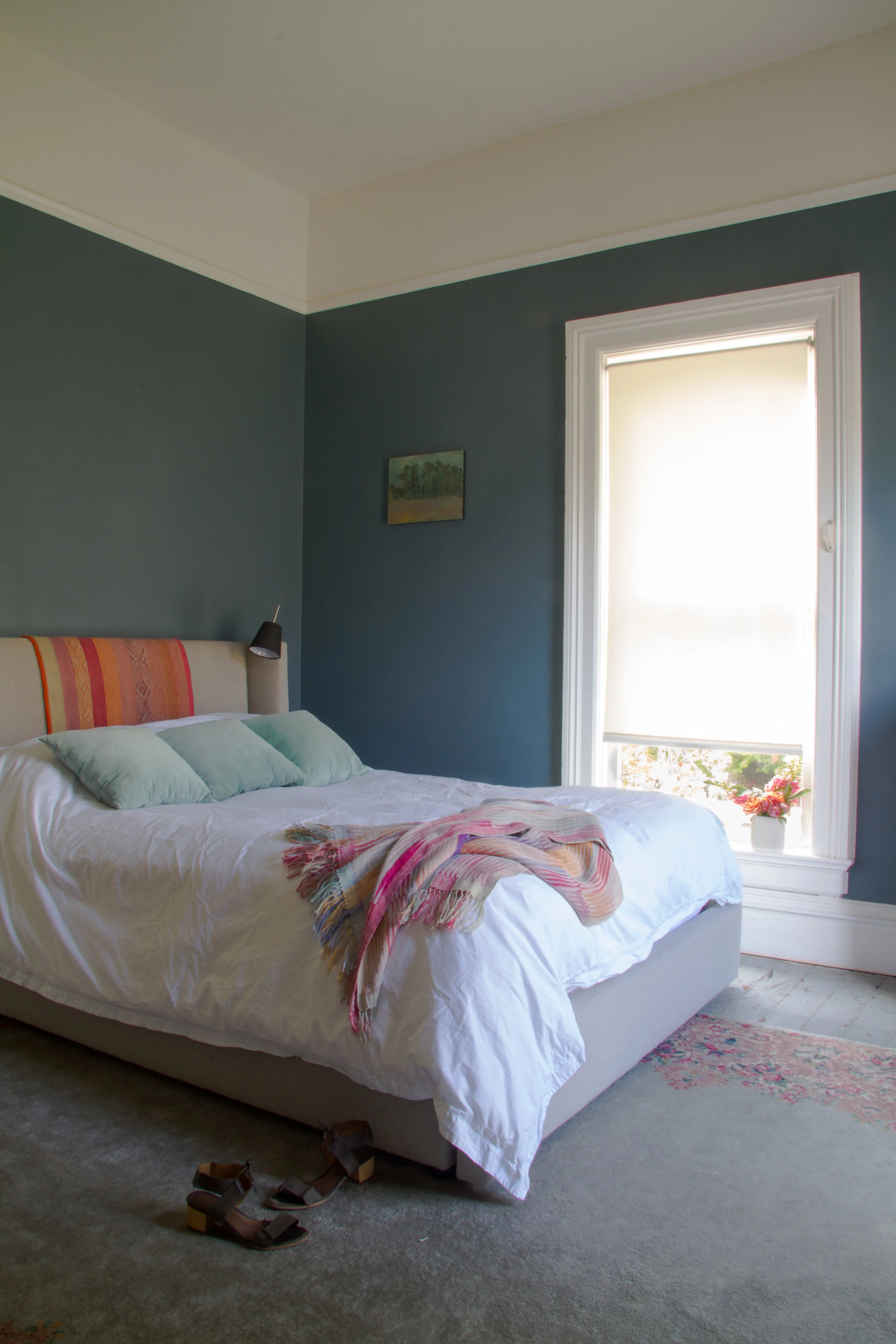 (16/21) A Peruvian throw over the master bedroom headborad is from Lock's store, as is the woven one. The painting was her first of many by local artist Brian Rounds . Walls are Benjamin Moore Blue Dusk.