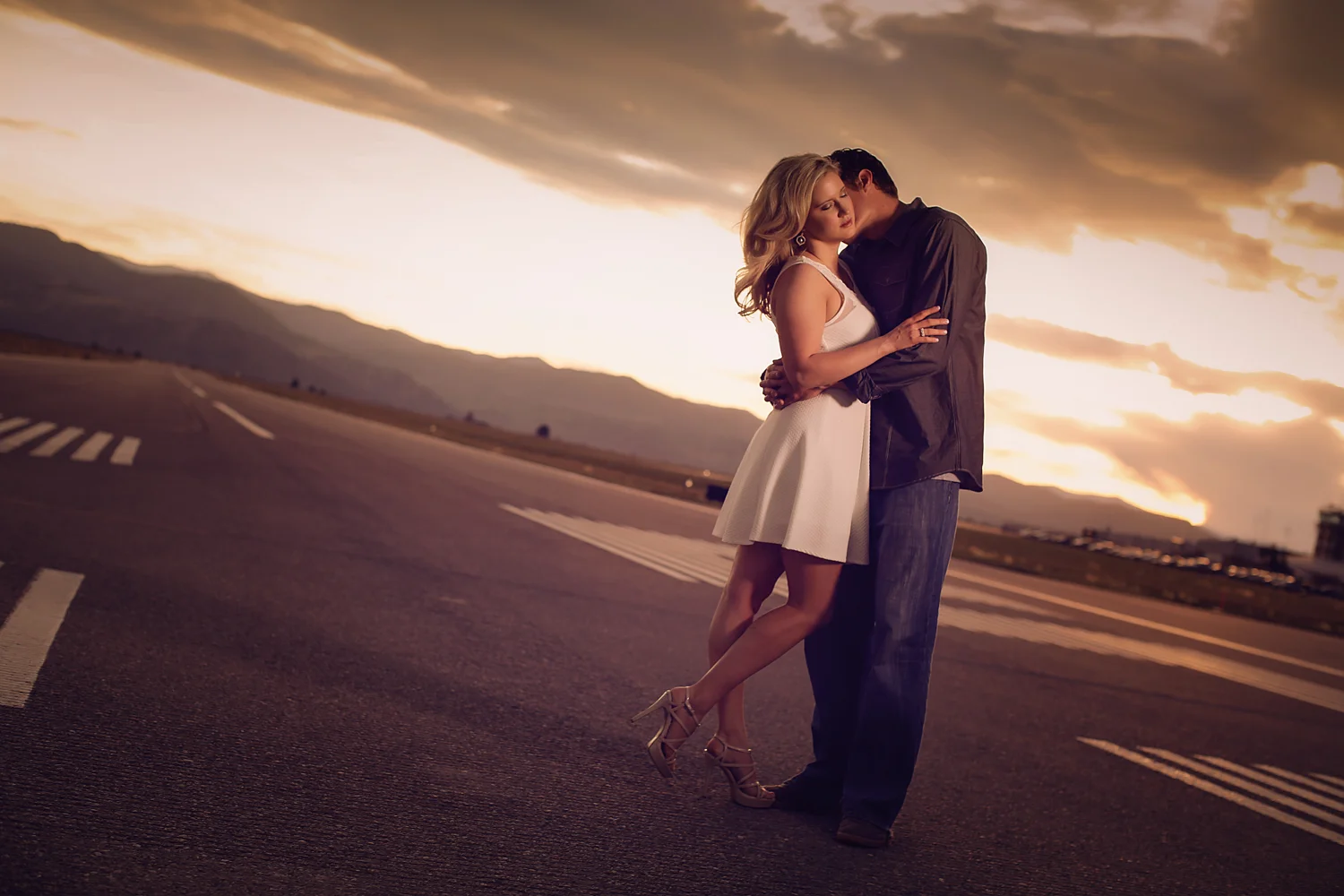 Wedding photo of couple kissing on airport runway