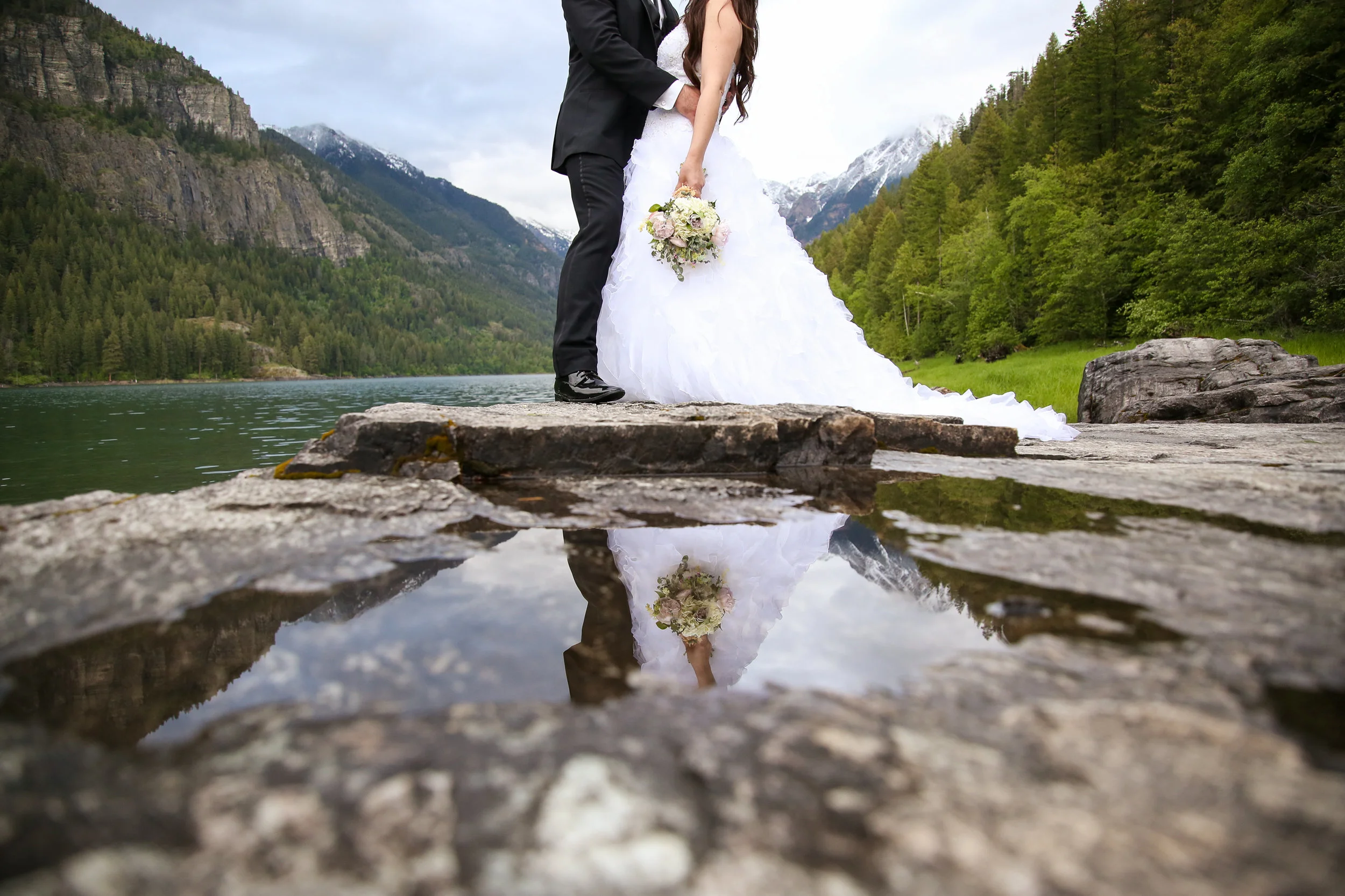 Bride and groom reflected in water at a Montana mountain lake