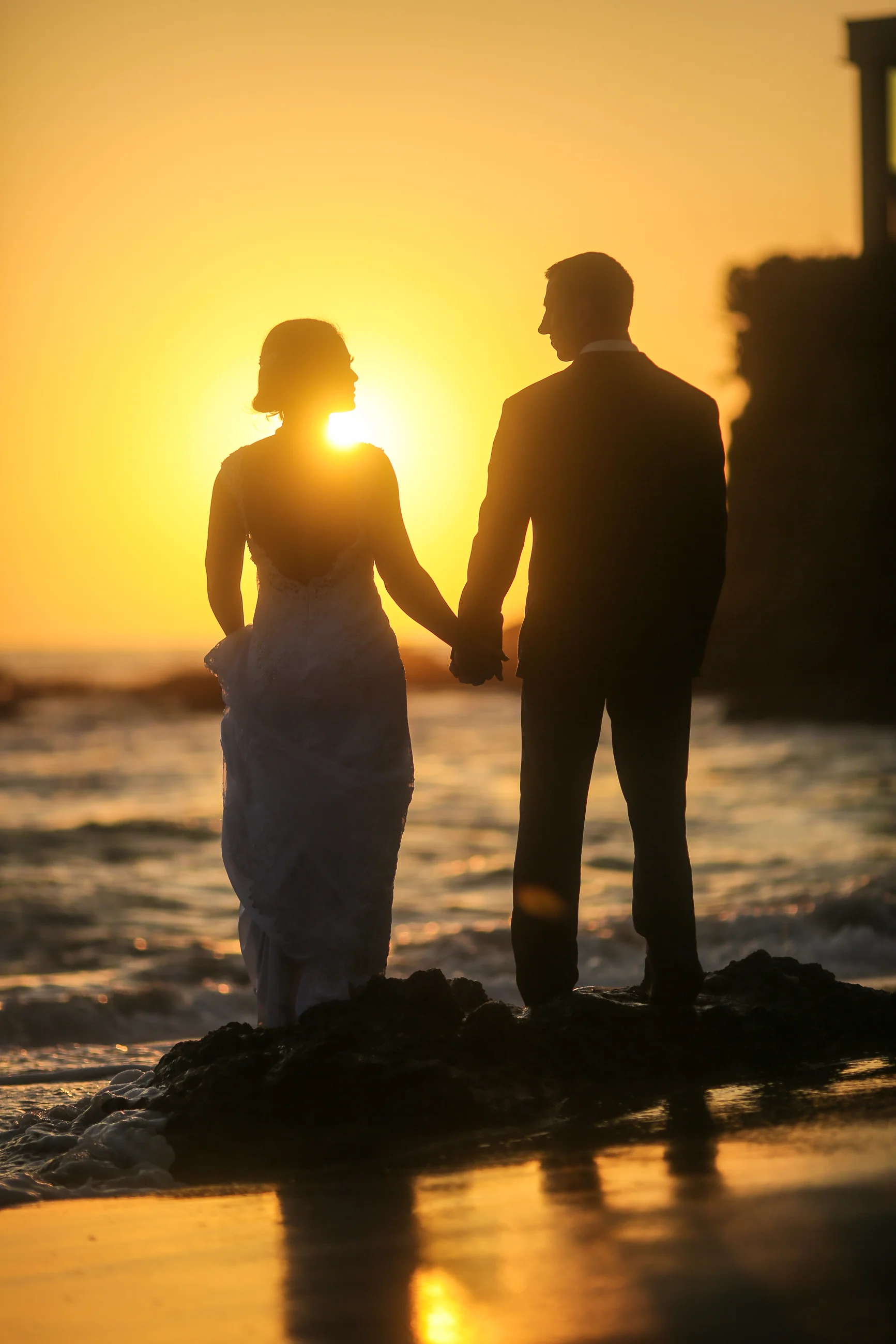 Bride and groom at the ocean at sunset in Huntington Beach California