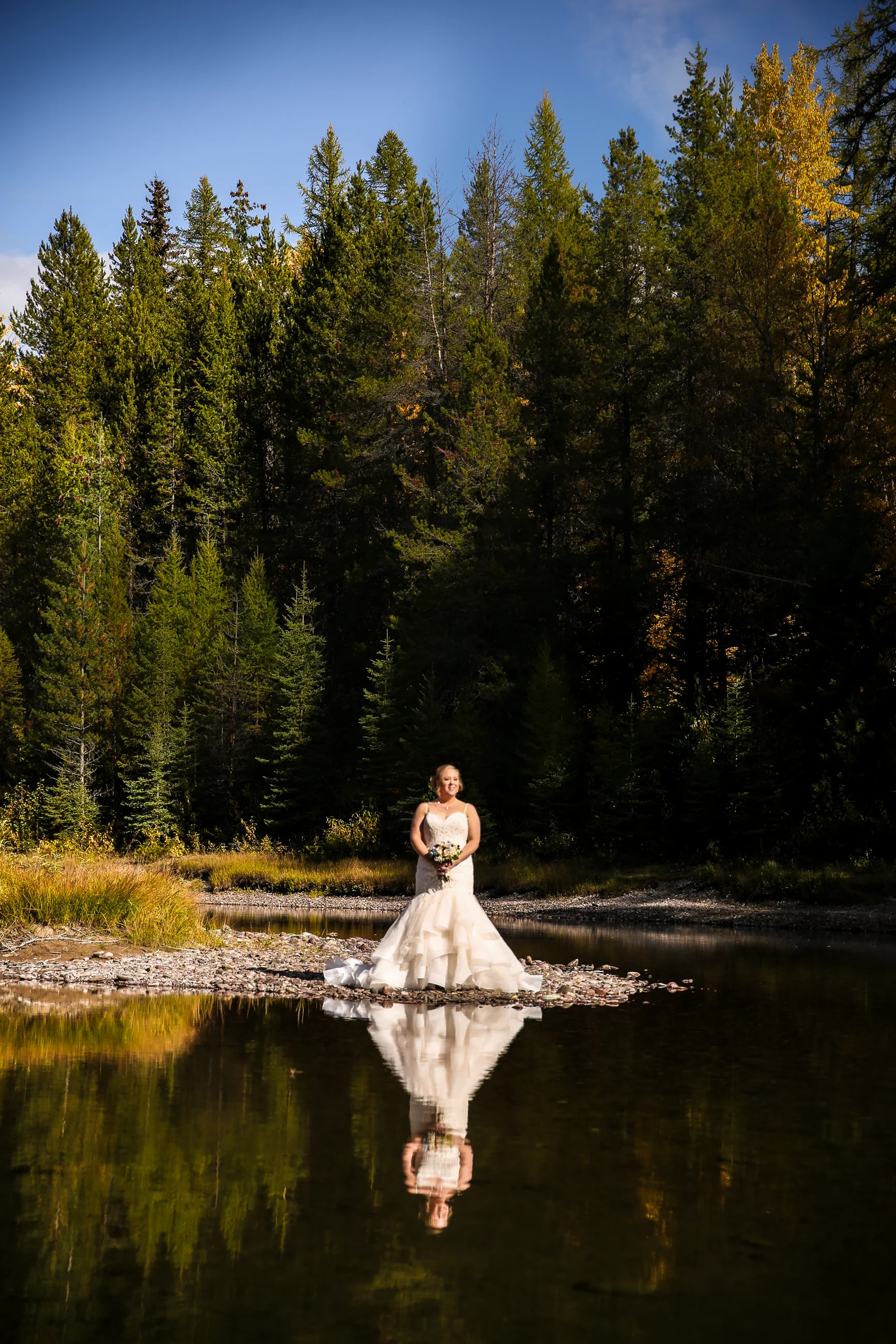Bride in glacier national park by the side of the lake with reflection in the water