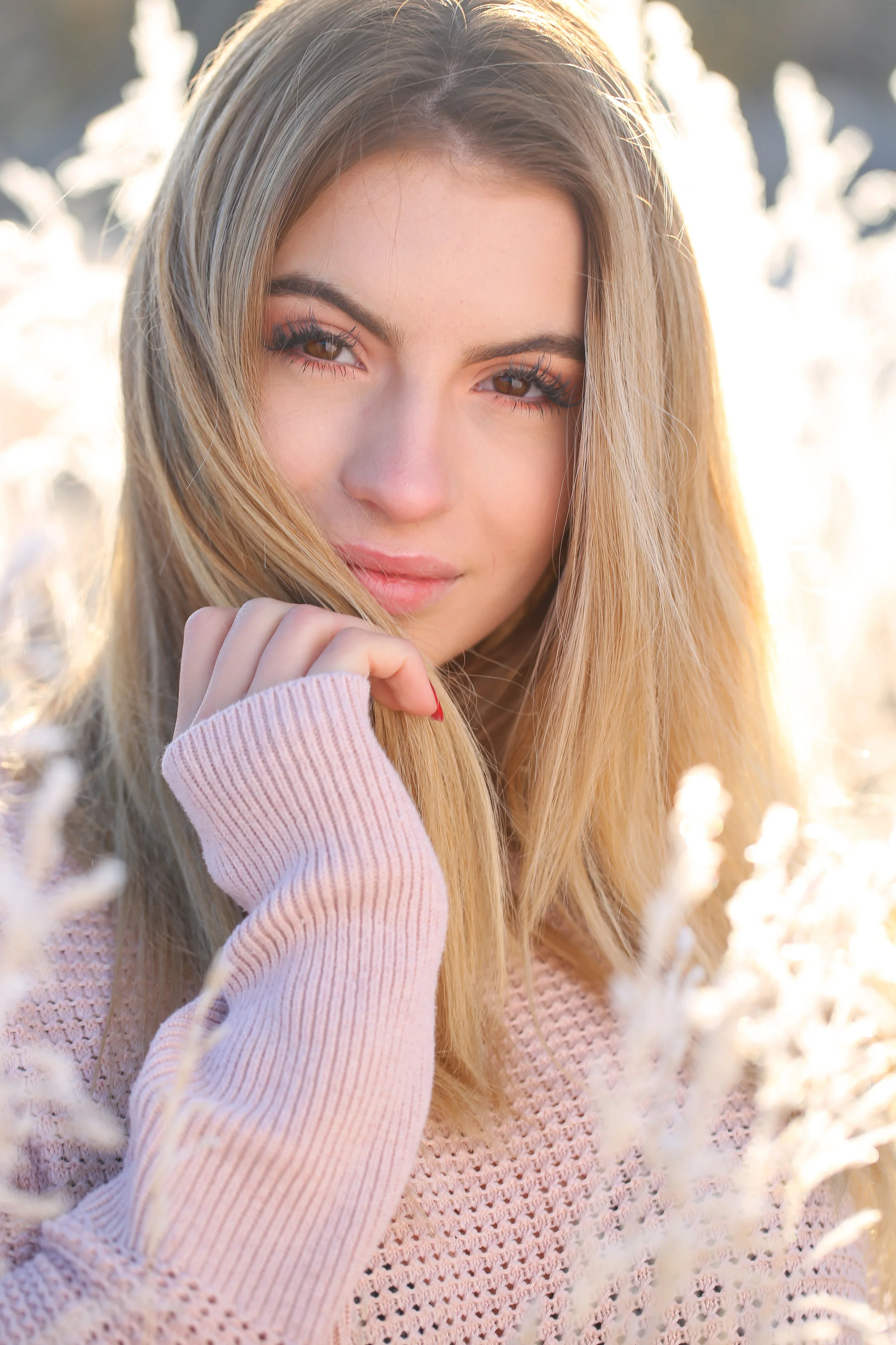 Senior portrait of Montana high school senior in pink sweater in frost covered grass at sunrise