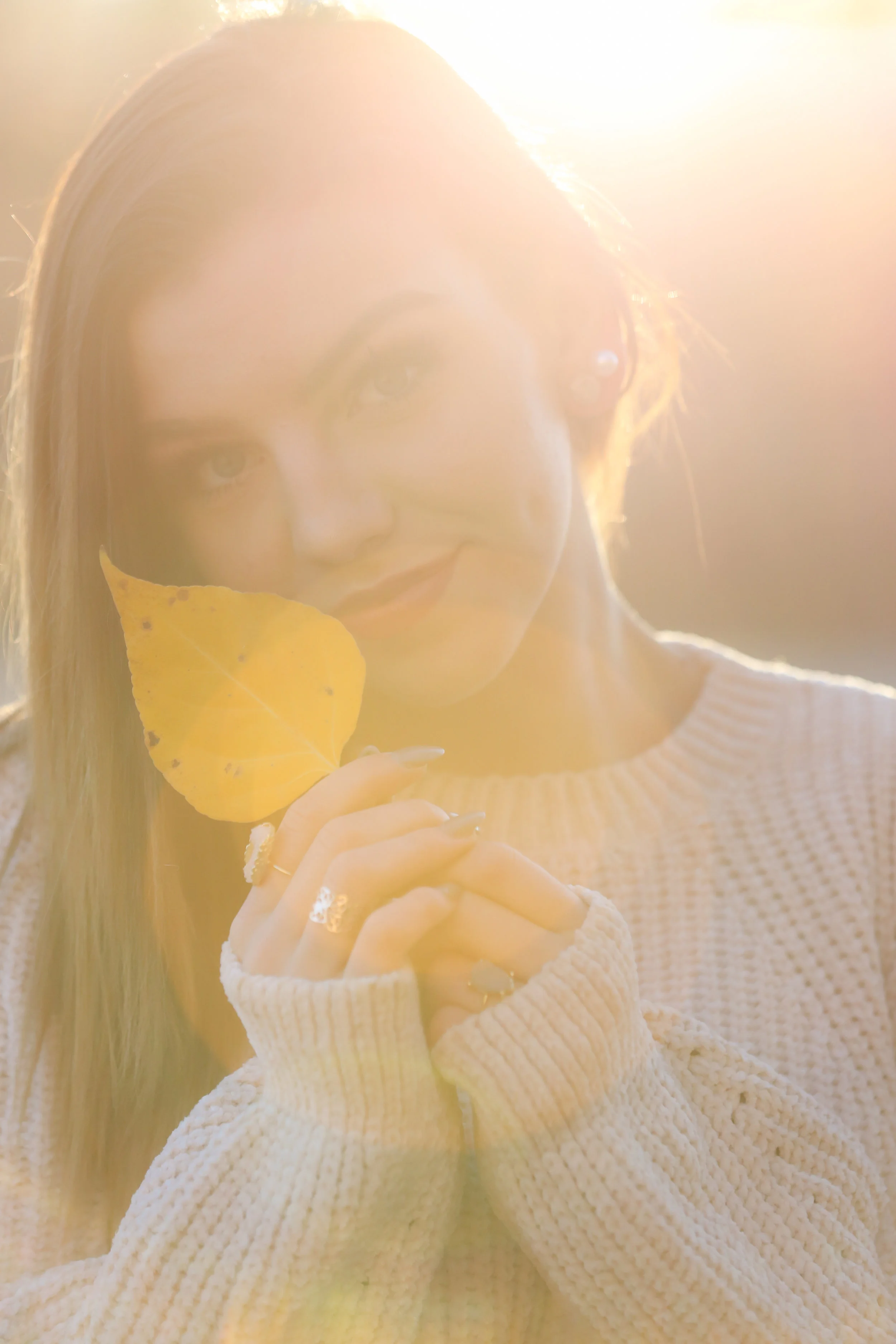 Senior portrait of Montana high school senior in a sweater holding at yellow leaf