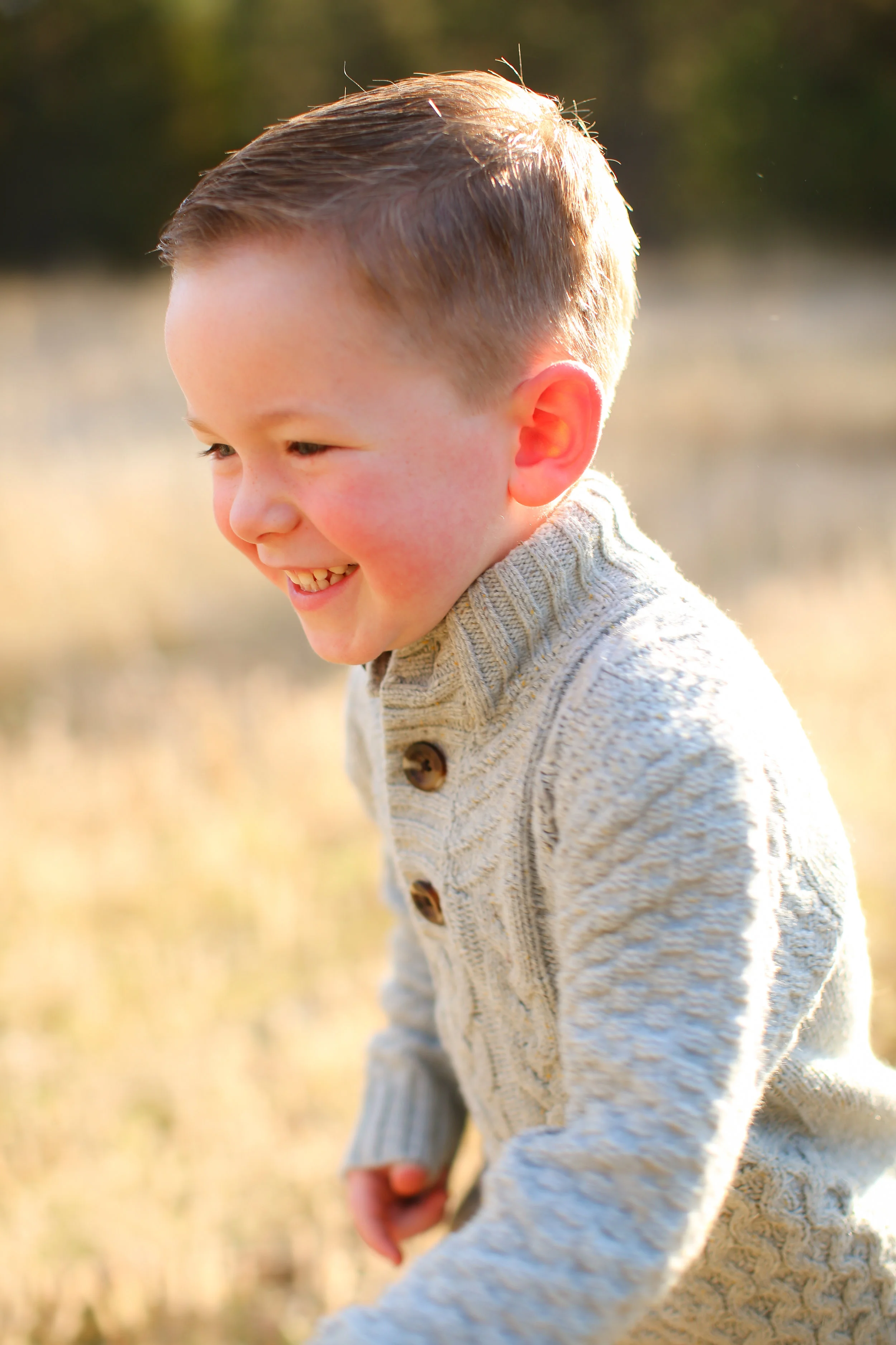 Family portrait of family in Montana boy running in grass field at sunset
