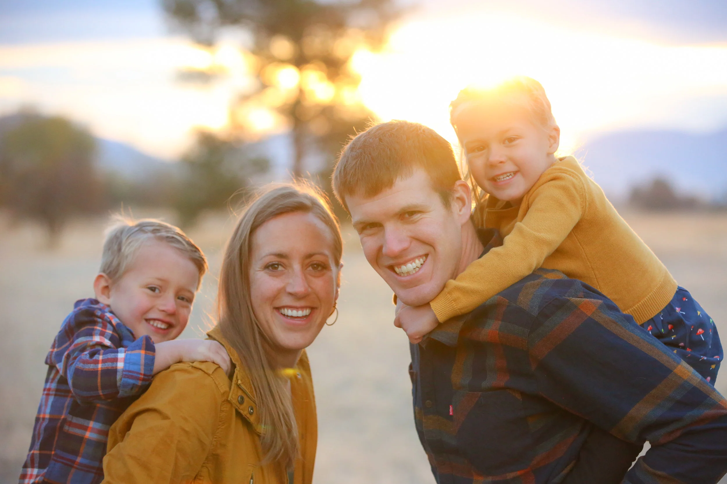 Family portrait of family in Montana smiling in grass field at sunset