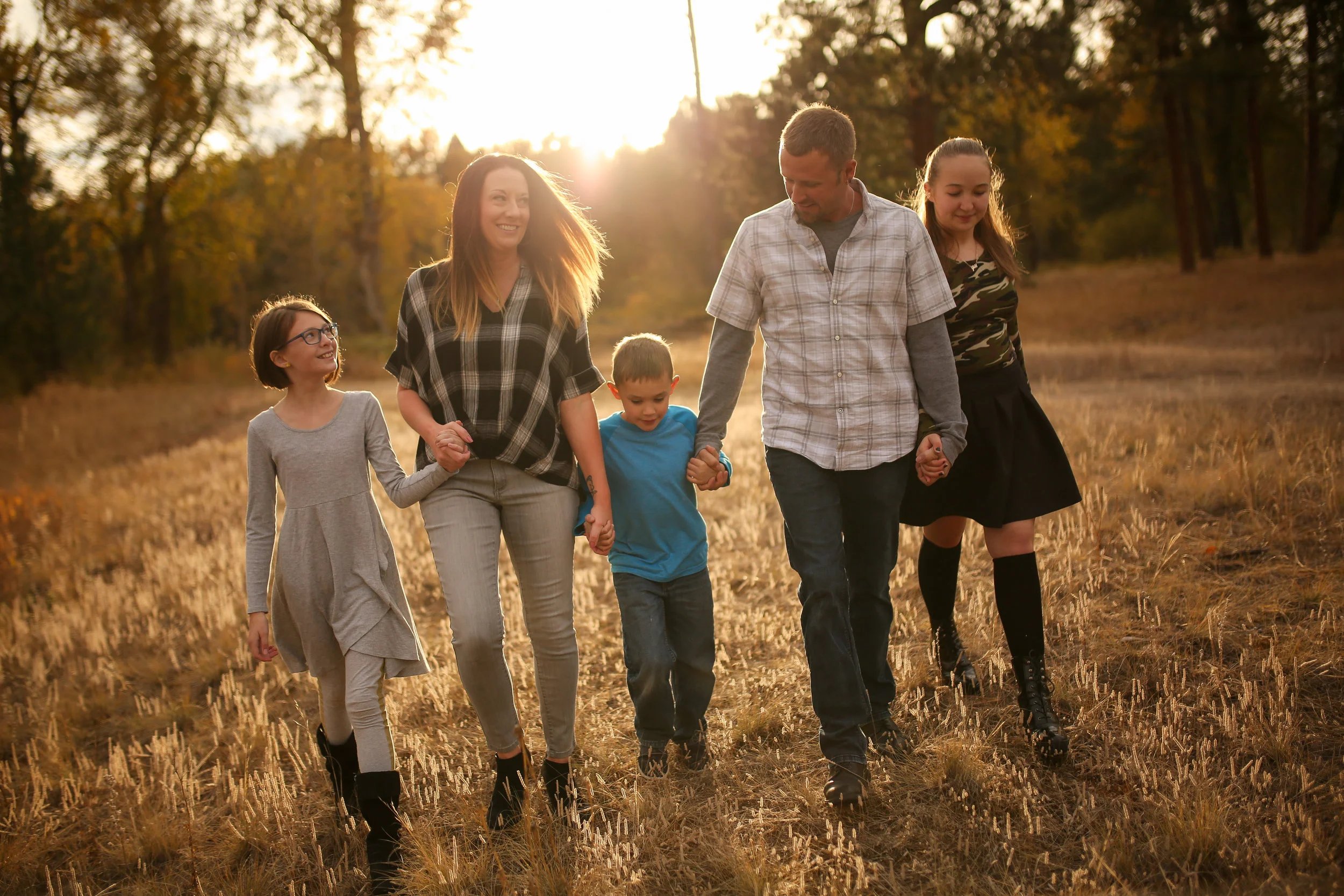 Family portrait of family in Montana walking in grass field at sunset