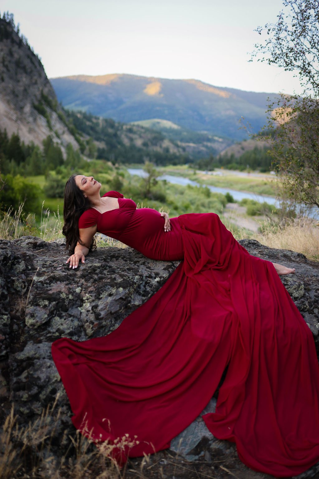 Pregnant mom laying on rock in red gown.jpg