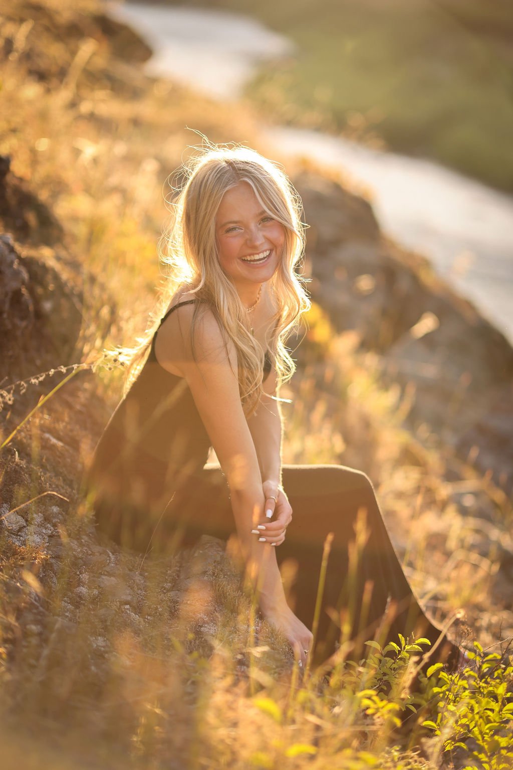 Senior portrait of girl sitting on mountain rock formation with river in background.jpg