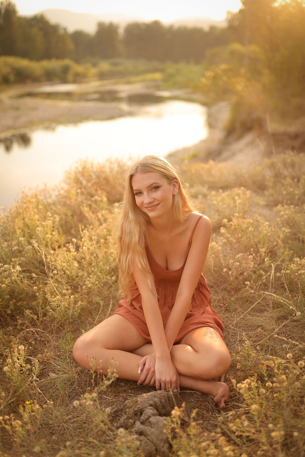 Gorgeous senior portrait of girl sitting next to river at golden hour.jpg