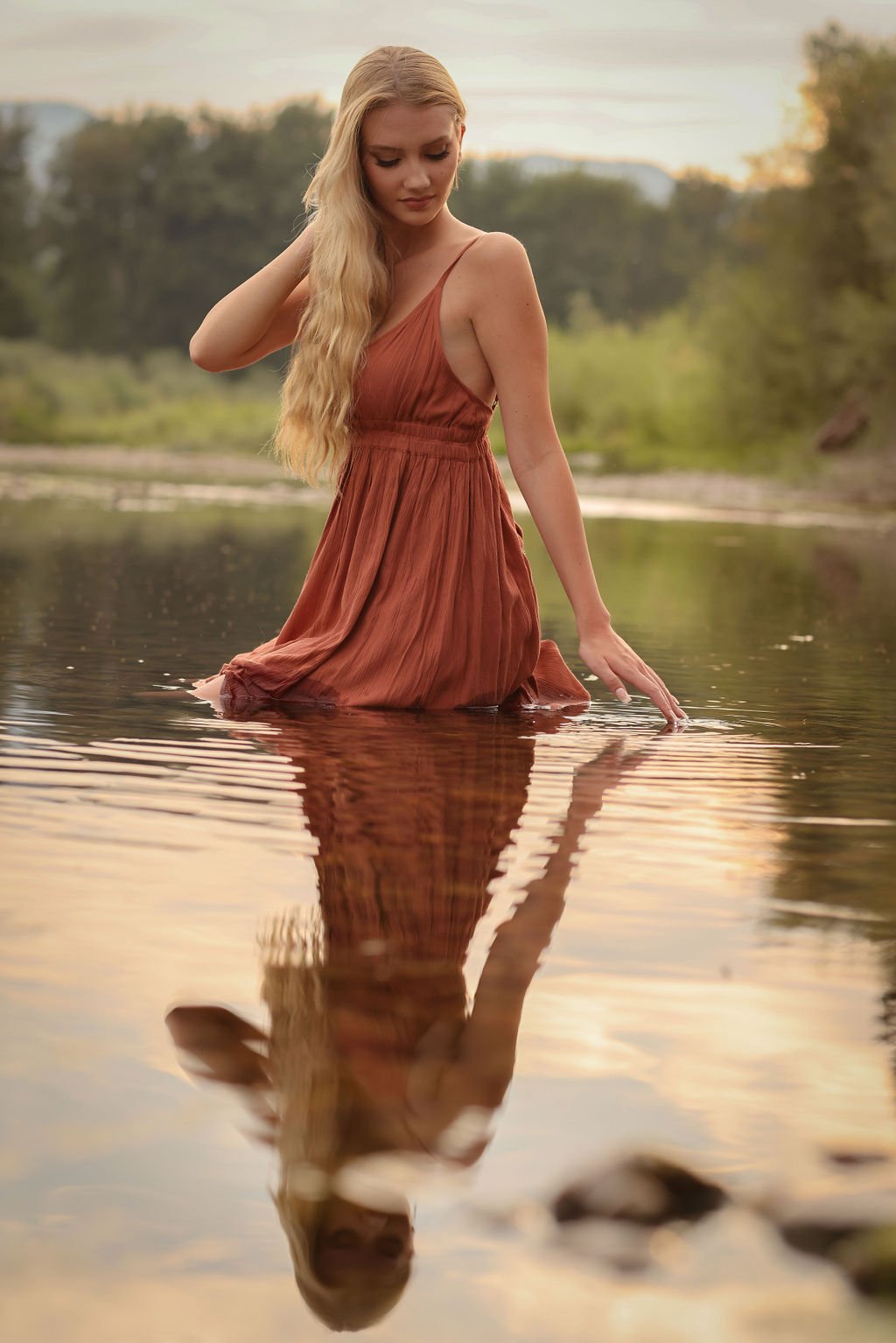 Creative senior portrait ideas of girl sitting in Montana river with water reflection.jpg