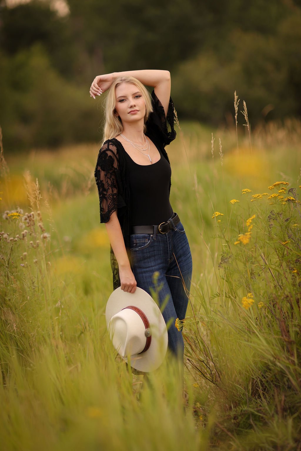 Montana senior portrait holding hat in grass field.jpg