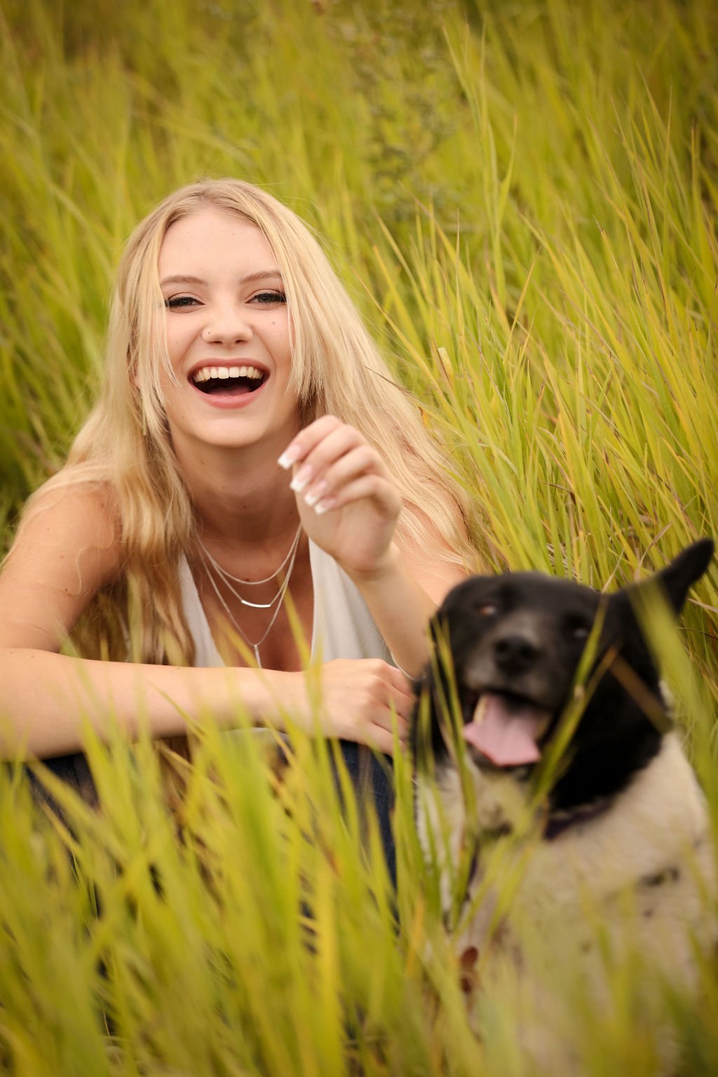 Senior girl laughing next to dog in field.jpg