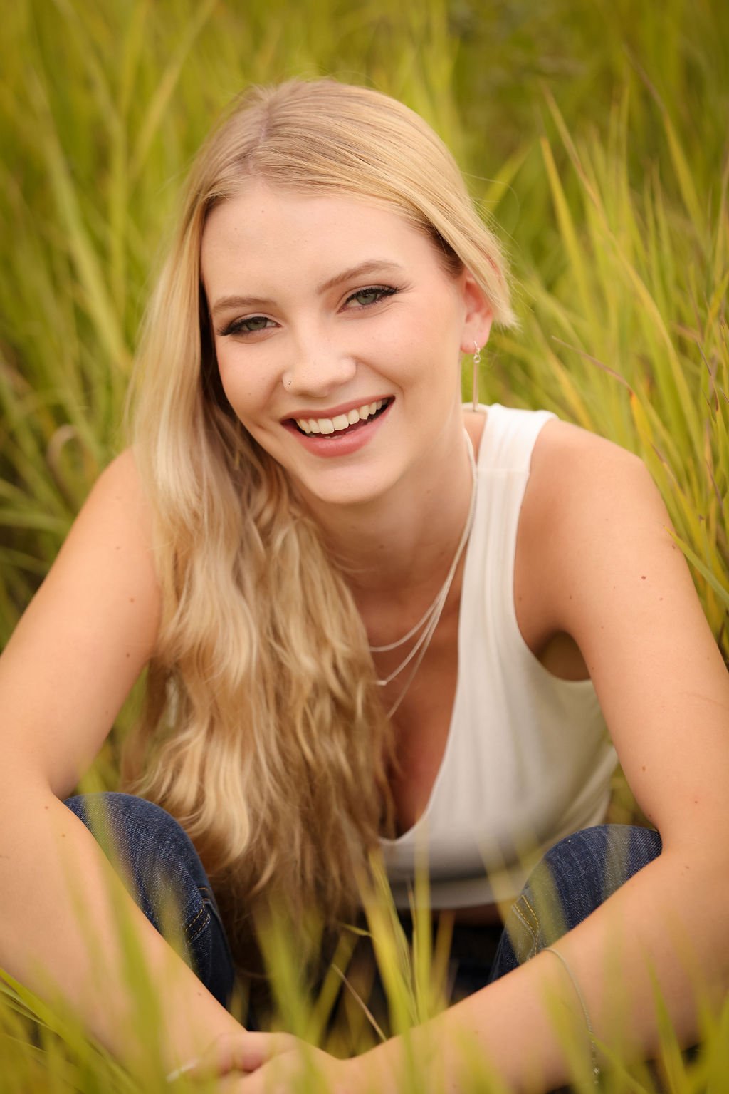 Montana high school senior smiling and sitting in green grass field.jpg