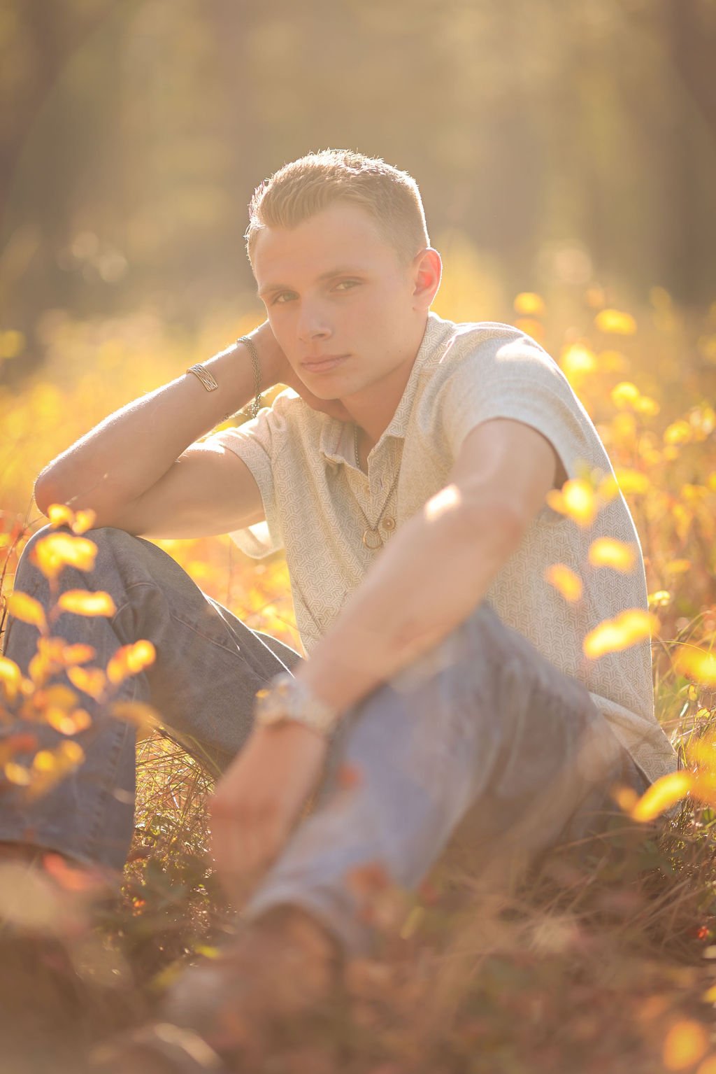 High school senior boy sitting in fall colored field.jpg