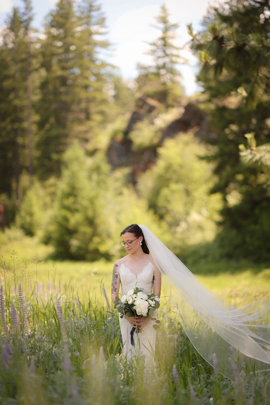 Bride with cathedral veil standing in Montana field at White Raven.jpg