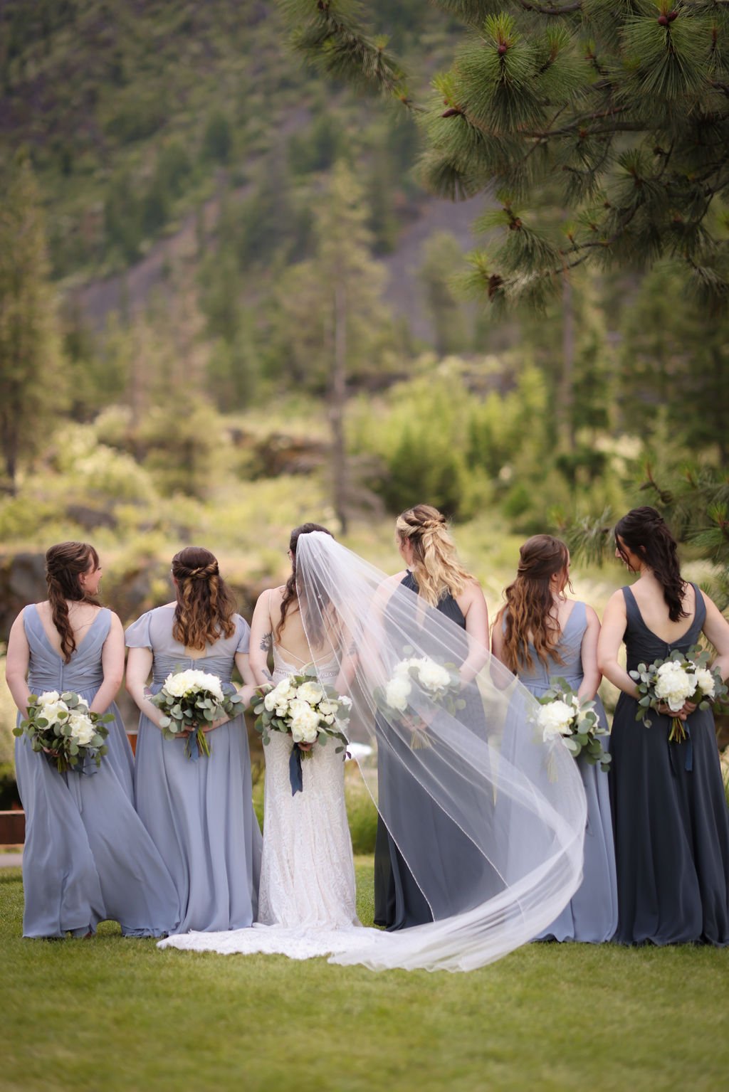 Bride and bridesmaids holding bouquets behind them at White Raven.jpg