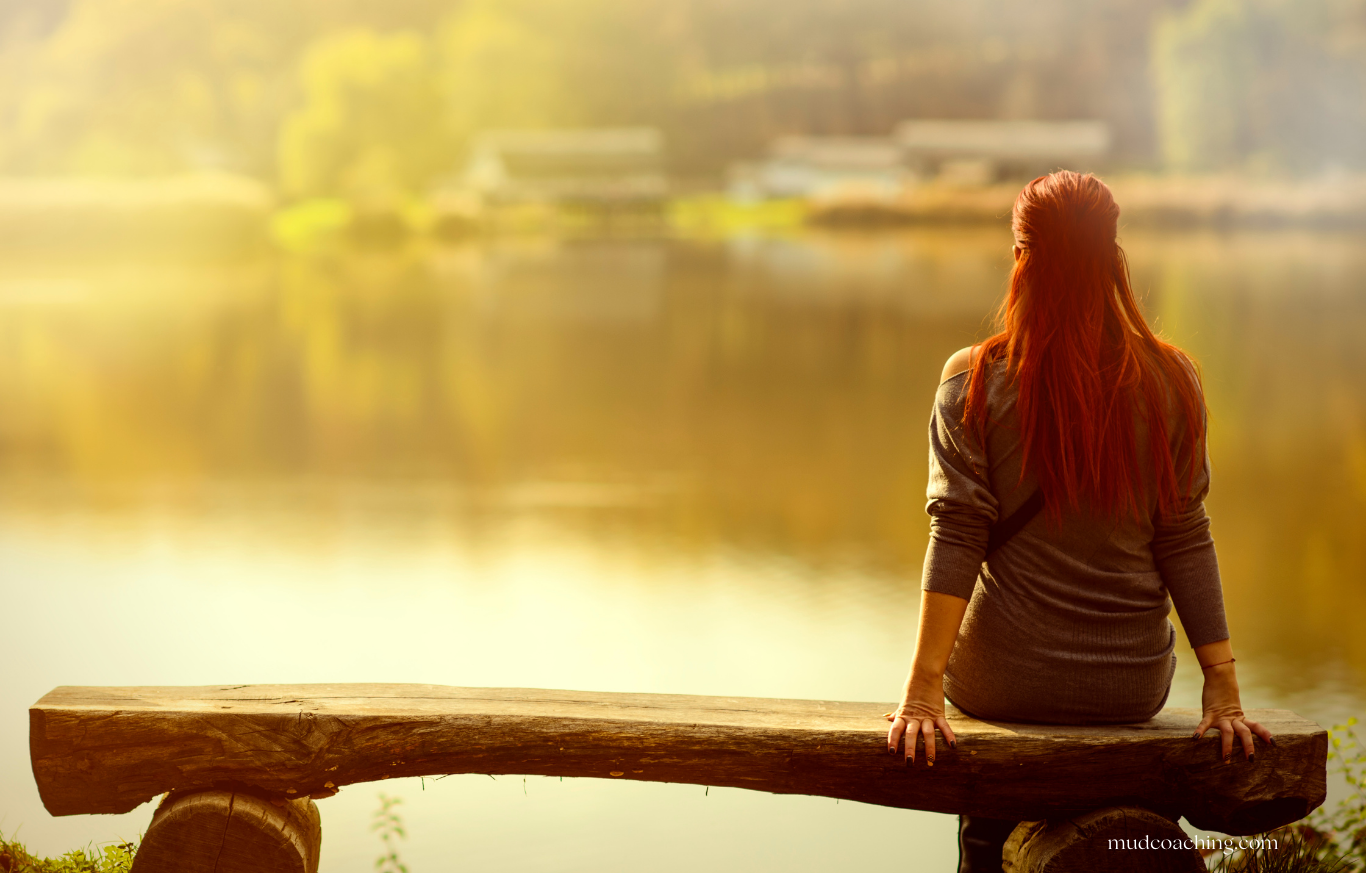 A woman sitting alone at a café, looking out a window in a quiet moment of reflection.