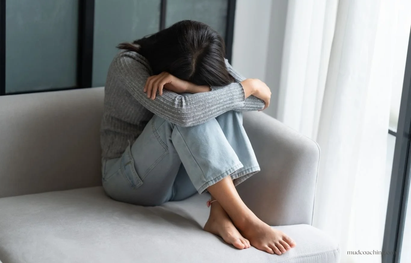 Woman sitting with head down in distress, representing feeling unprioritized and emotionally neglected in a relationship