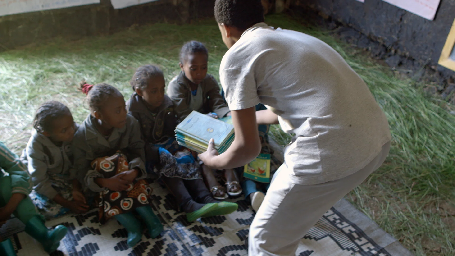 18-year-old Belihu hands out local language books to children during story reading time at the Mishig reading camp. (Photo credit: Max Greenstein / World Vision)