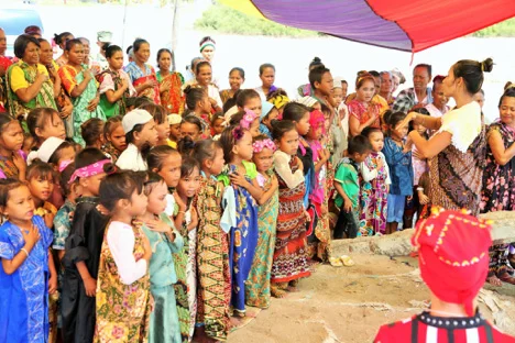 Teacher Sariba Abdulbasit leads Bajau young learners and their parents in singing the national anthem at the launching of AmB’s floating classroom. (March 2016)