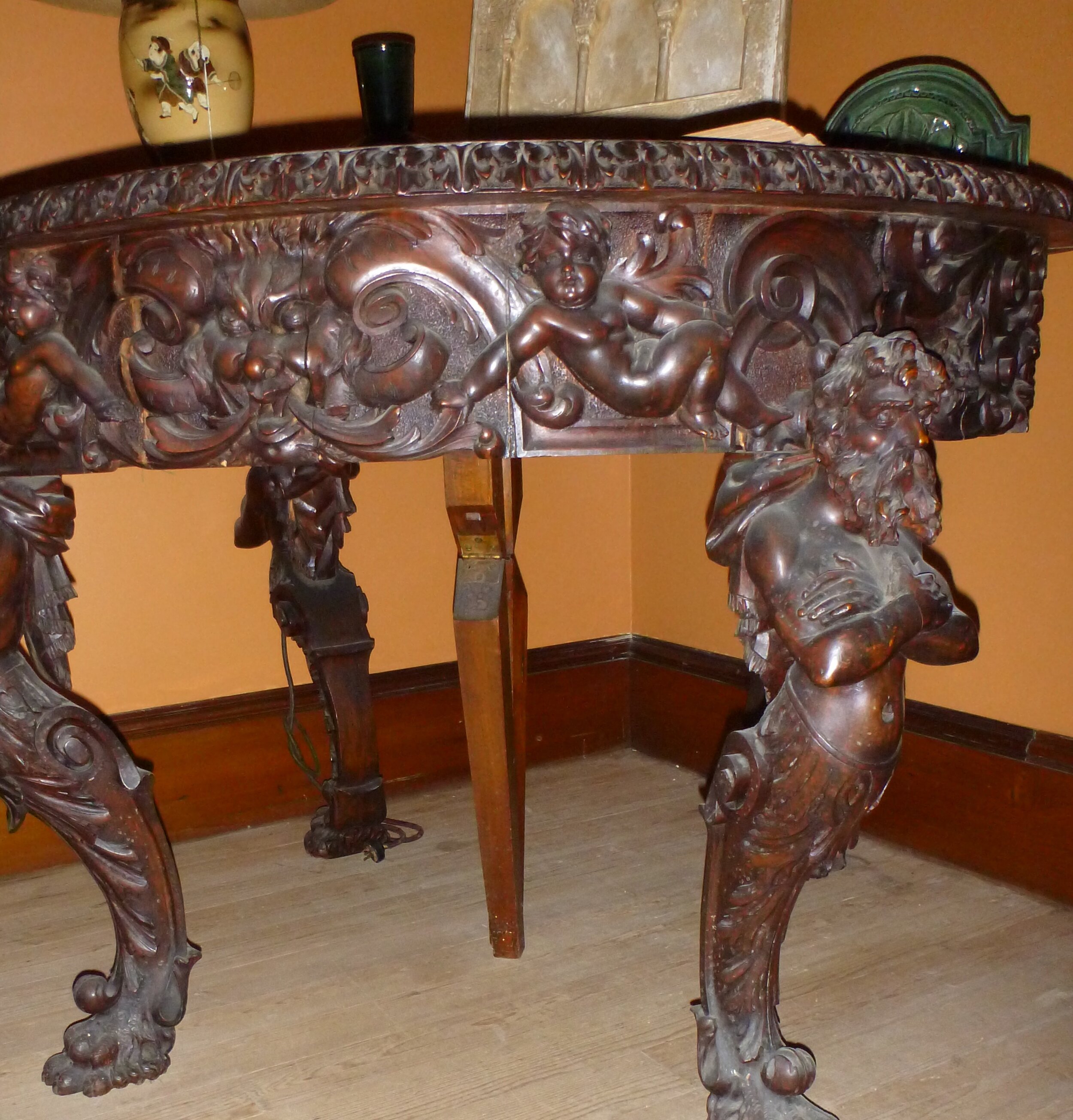 The furniture was heavy and massive and had elegant carvings of strong men for legs holding up the table top